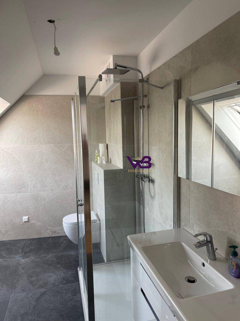 Modernes Badezimmer mit begehbarer Dusche, Waschbecken und Dachschräge.