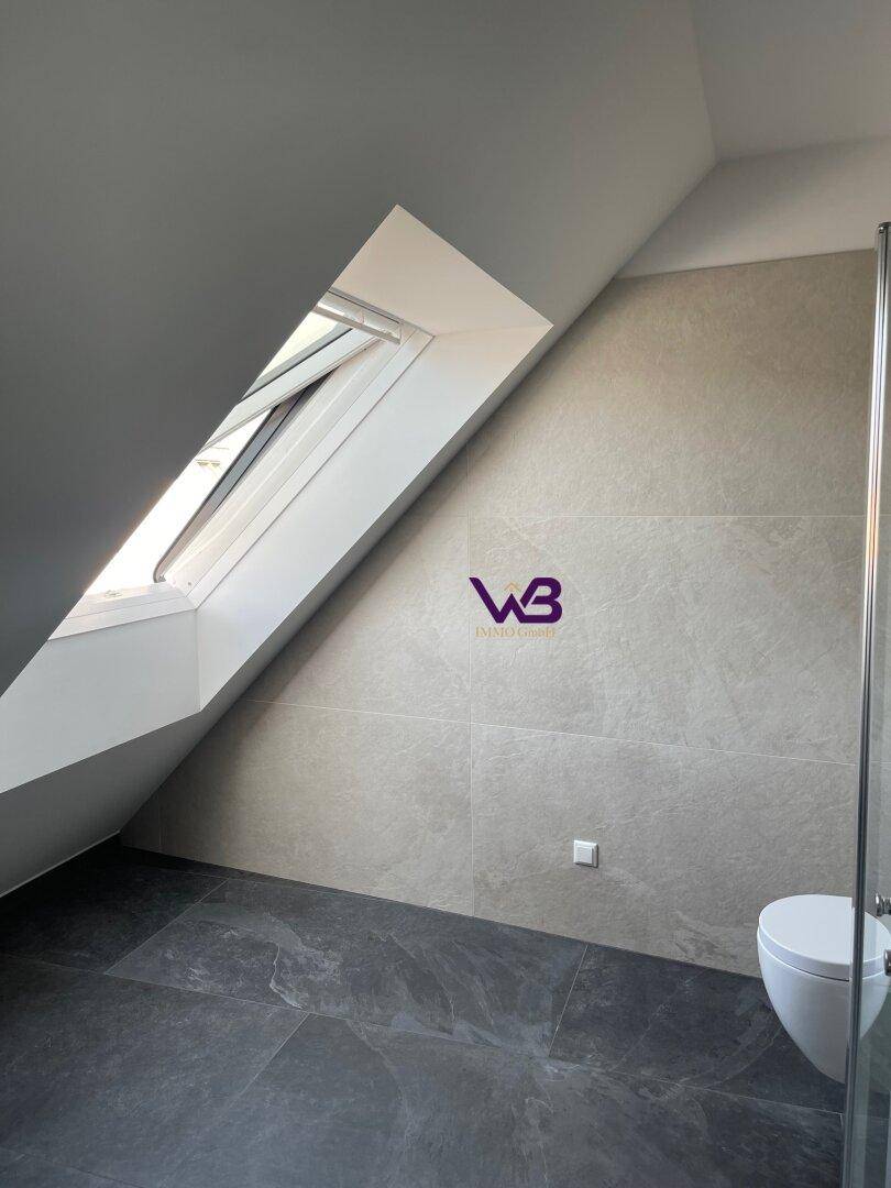 Helles Badezimmer mit Dachfenster, grauen Fliesen und moderner Ausstattung.