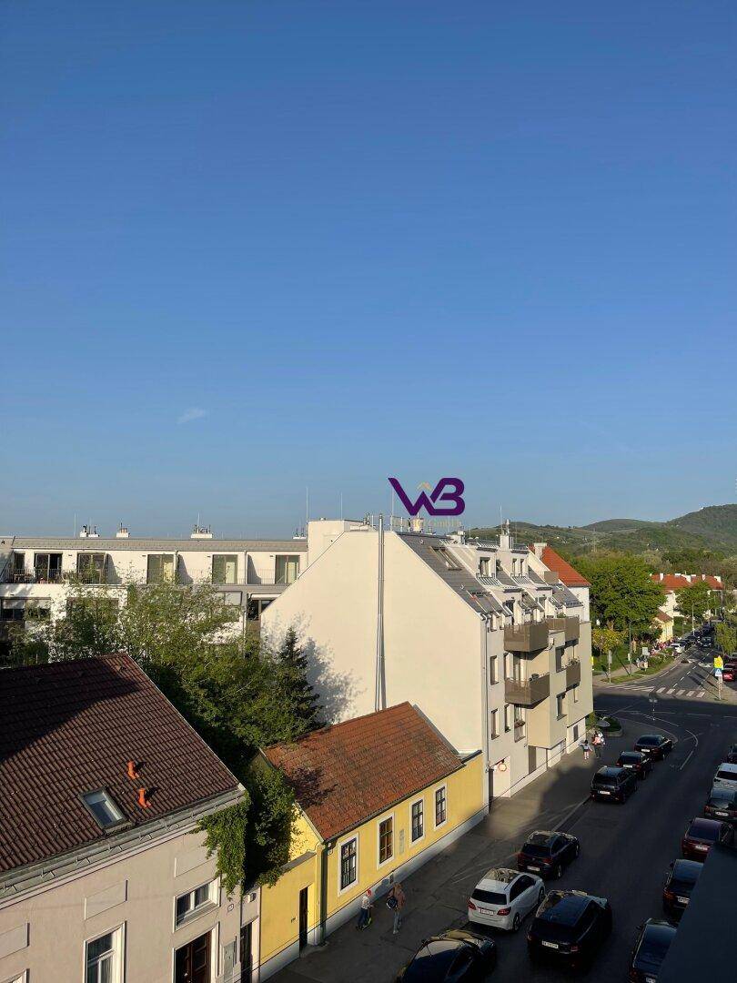 Weitläufiger Blick über die Stadt mit Wohngebäuden und einer belebten Straße.