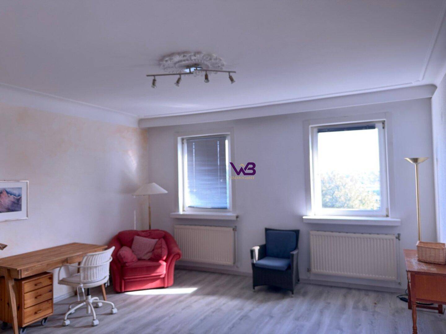 Helles Zimmer mit hellem Laminatboden, Stuckdecke und zwei Fenstern mit Blick ins Grüne.