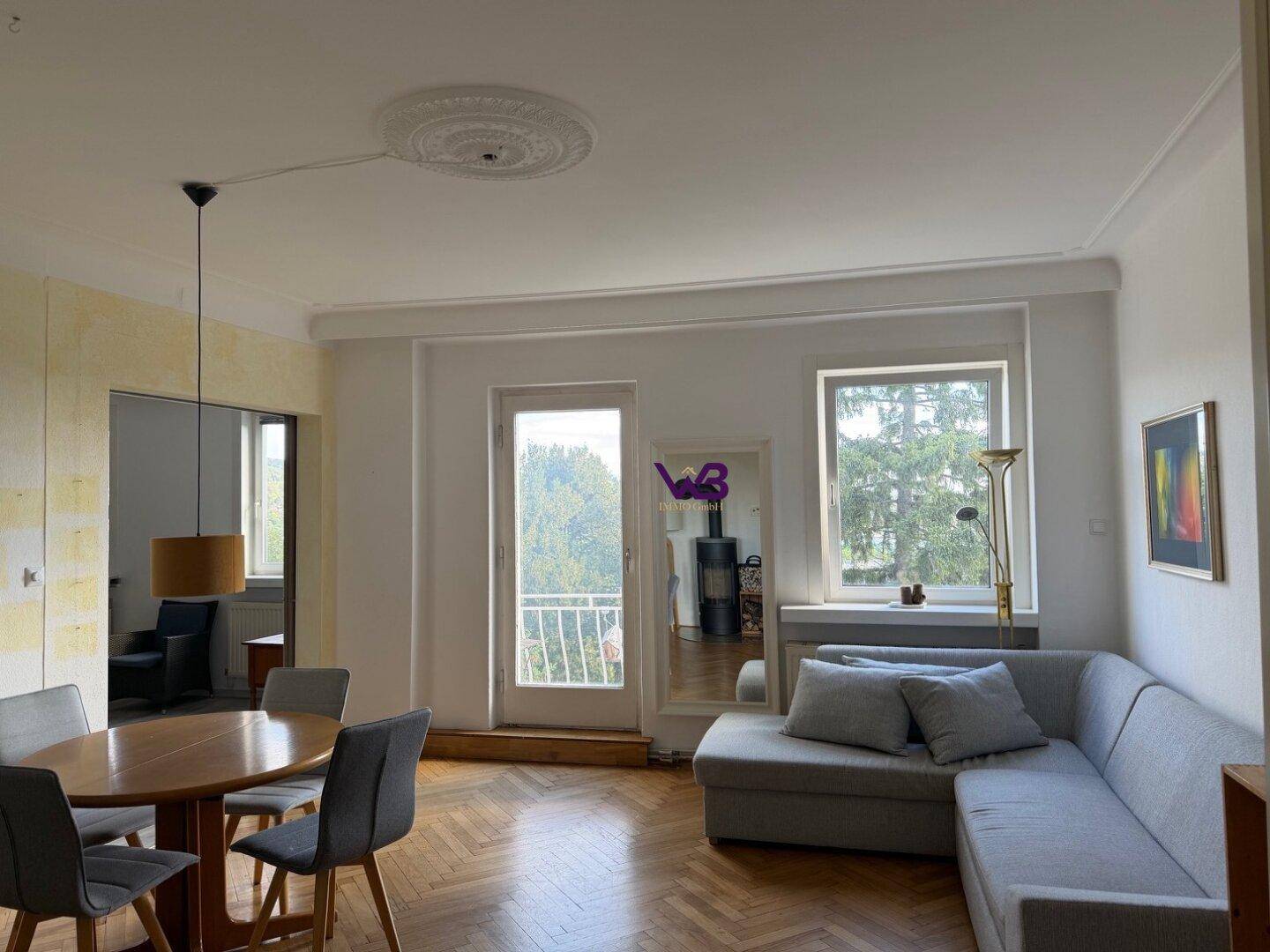 Heller Wohn-Essbereich mit Fischgrätparkett, Kaminofen und Zugang zu einem französischen Balkon.