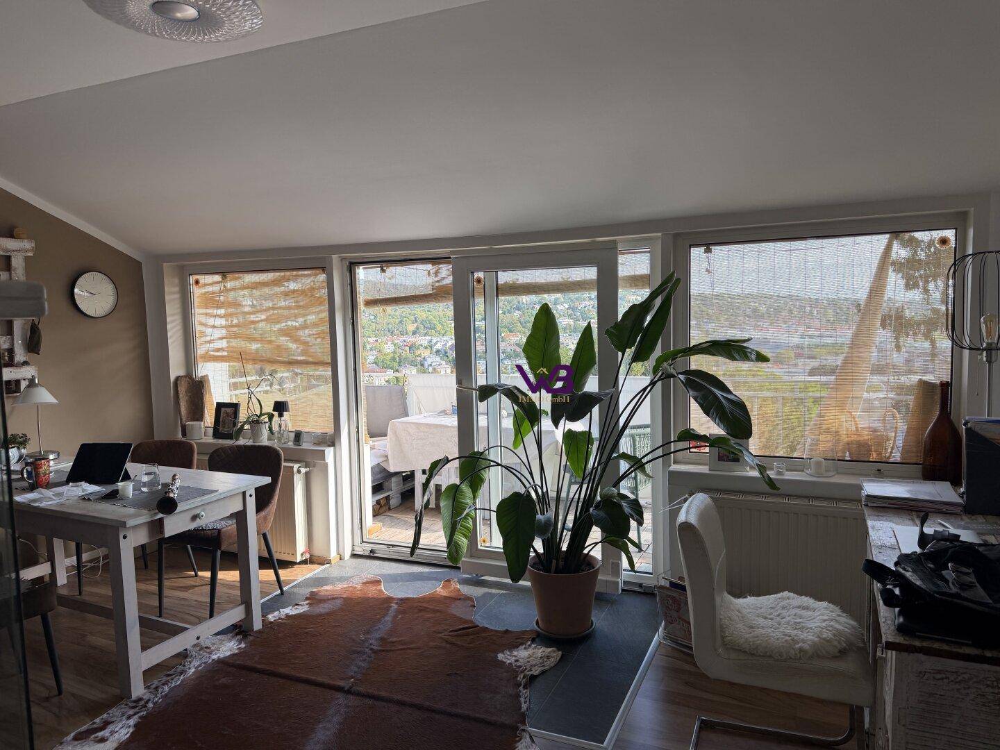 Heller Wohn-Essbereich mit großen Fenstern, Holzboden und Zugang zu einem Balkon mit Aussicht.