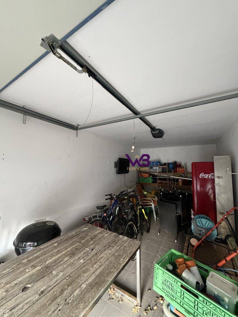 Geräumige Garage mit automatischem Torantrieb, Stauraum und verschiedenen Fahrrädern.