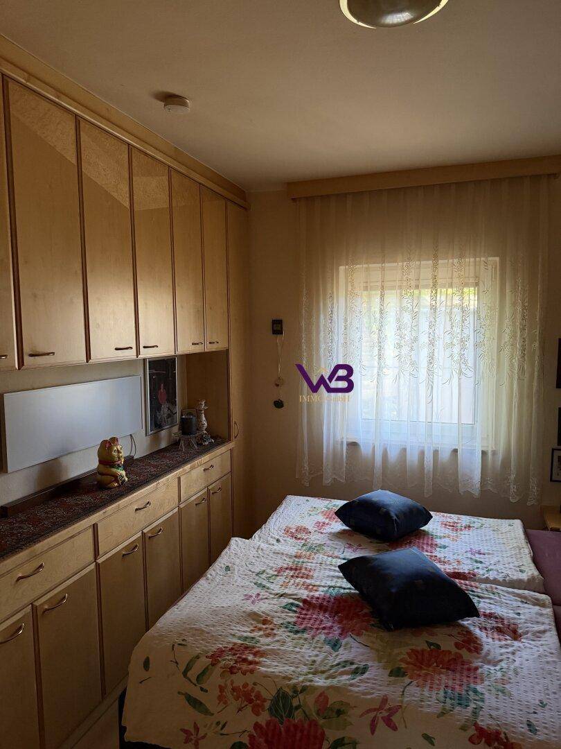 Schlafzimmer mit zwei Einzelbetten, Einbauschränken und einem Fenster mit Vorhängen.