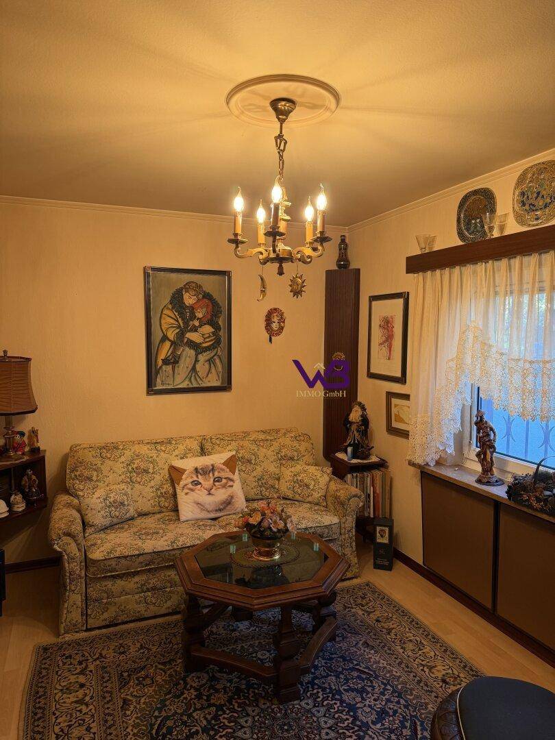 Gemütliches Wohnzimmer mit Sofa, Couchtisch, Kronleuchter und traditioneller Dekoration.