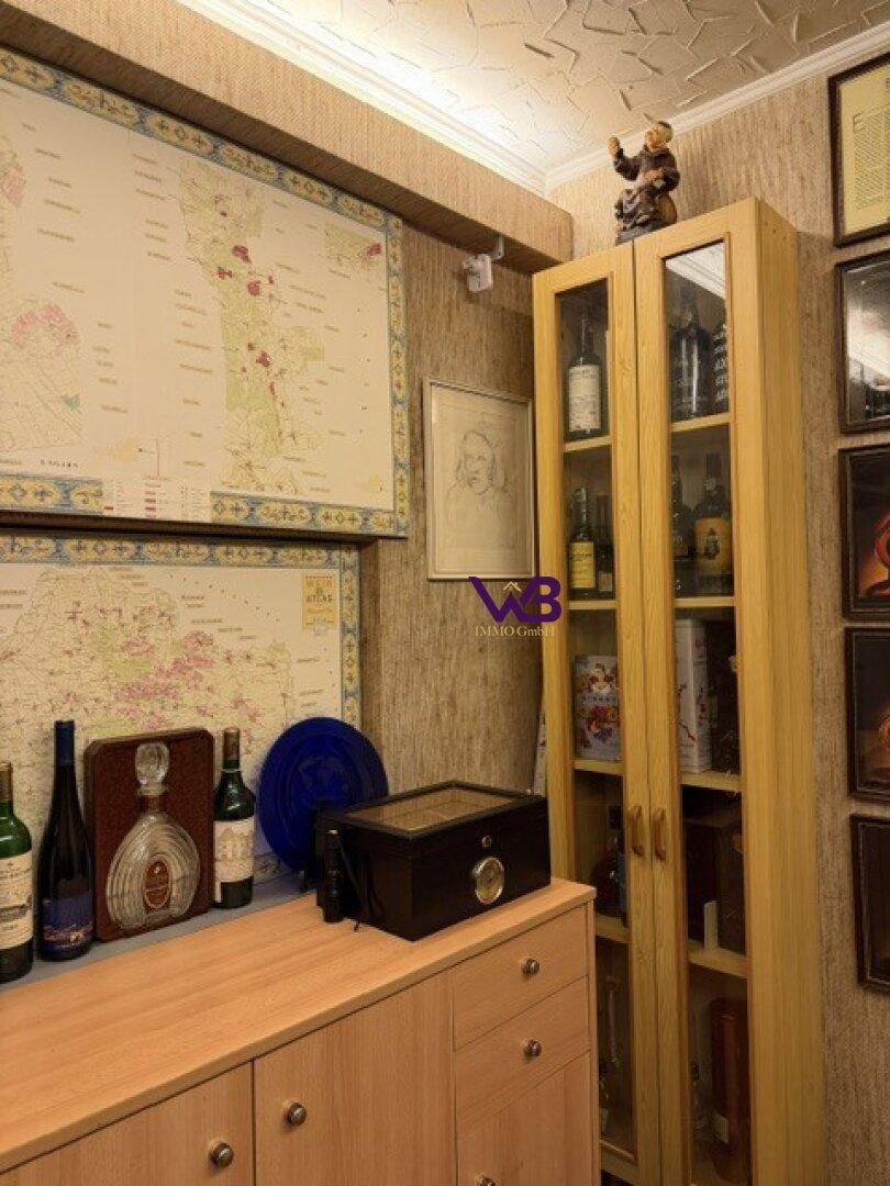 Lagerraum mit Holzschränken, Weinflaschen und dekorativen Landkarten an der Wand.