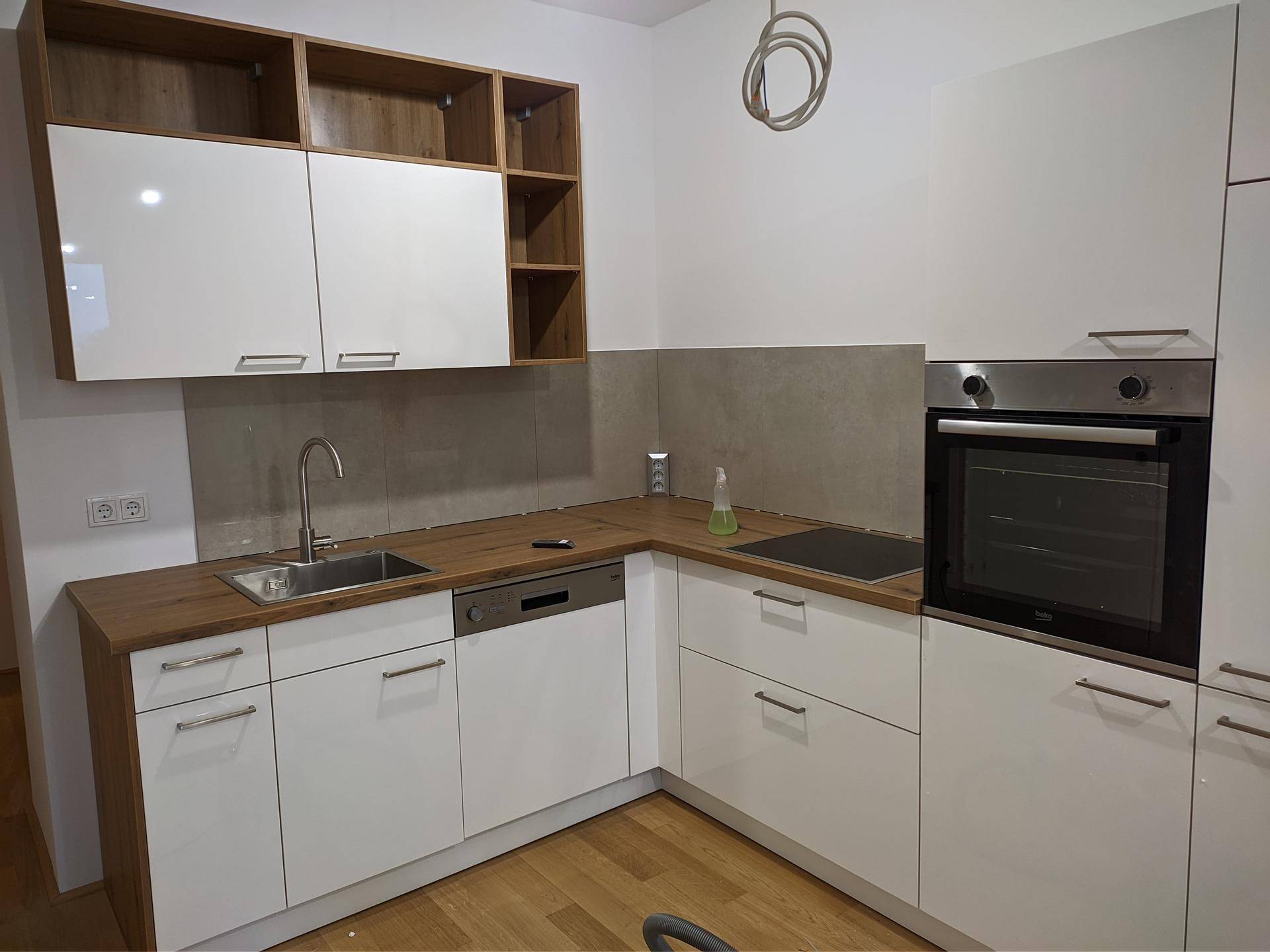 Moderne Einbauküche mit weißen Hochglanzfronten, Holzarbeitsplatte und integrierten Geräten.