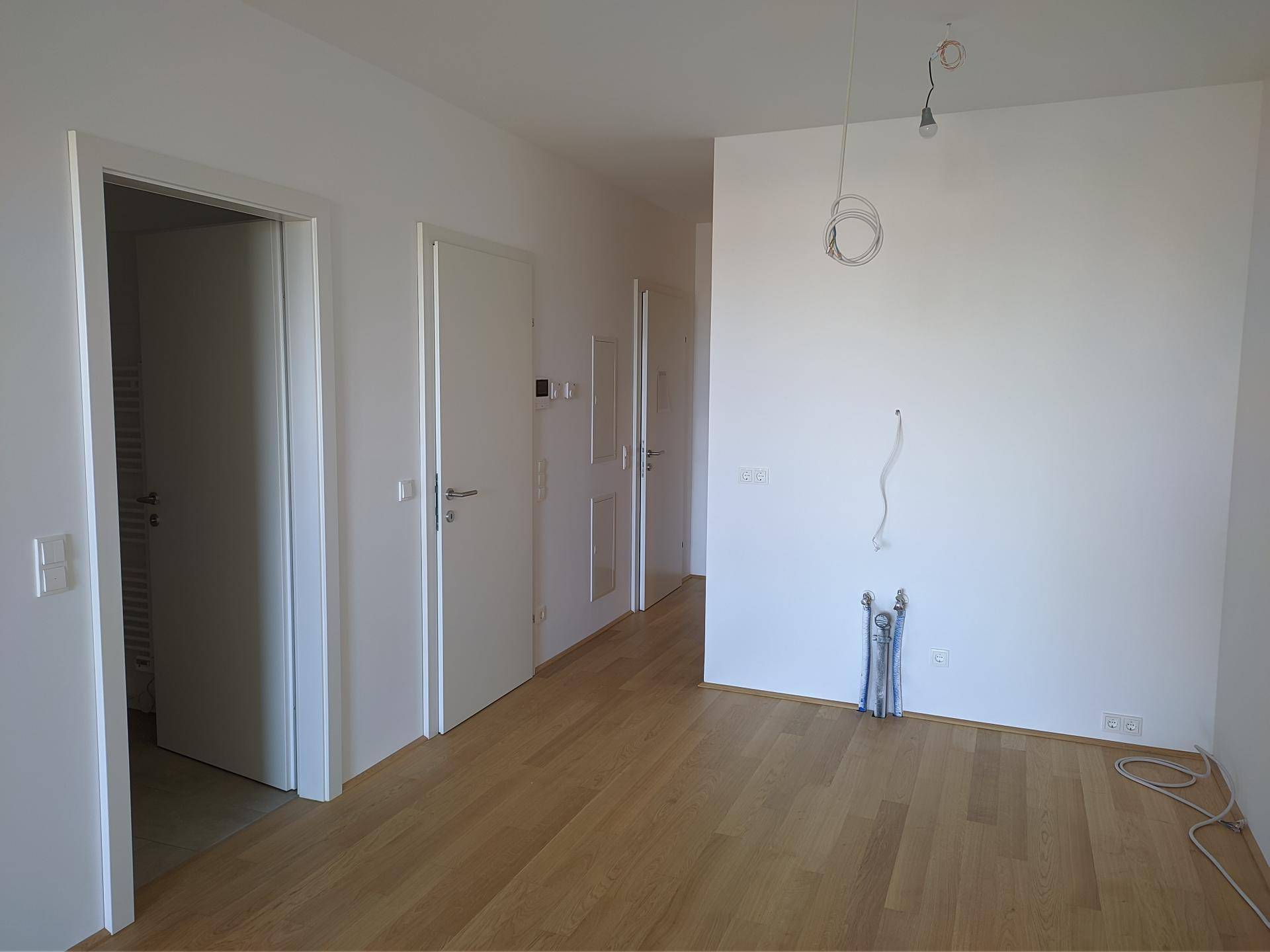 Heller Flur mit Holzboden und mehreren Türen, der zu verschiedenen Räumen führt.