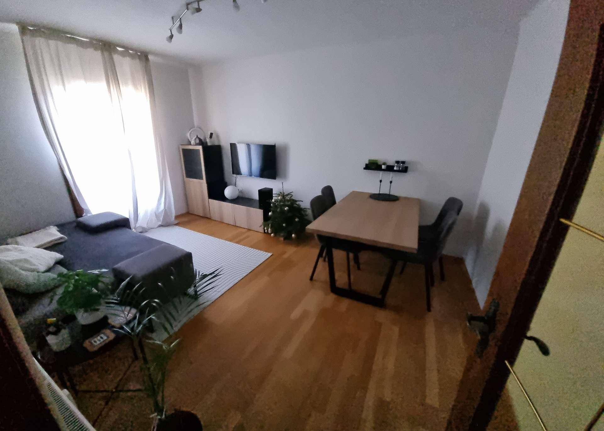 Geräumiger Wohn-Essbereich mit Parkettboden, bequemer Couch und einem Essbereich für mehrere Personen.