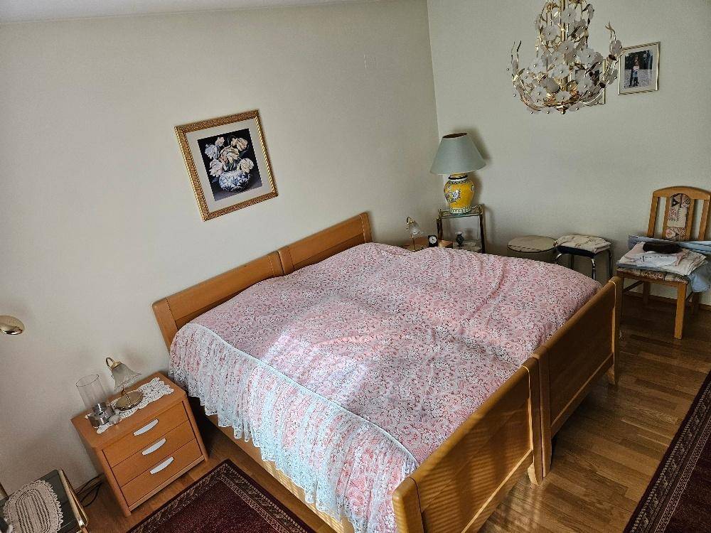 Schlafzimmer mit Doppelbett, Parkettboden und klassischem Kronleuchter.
