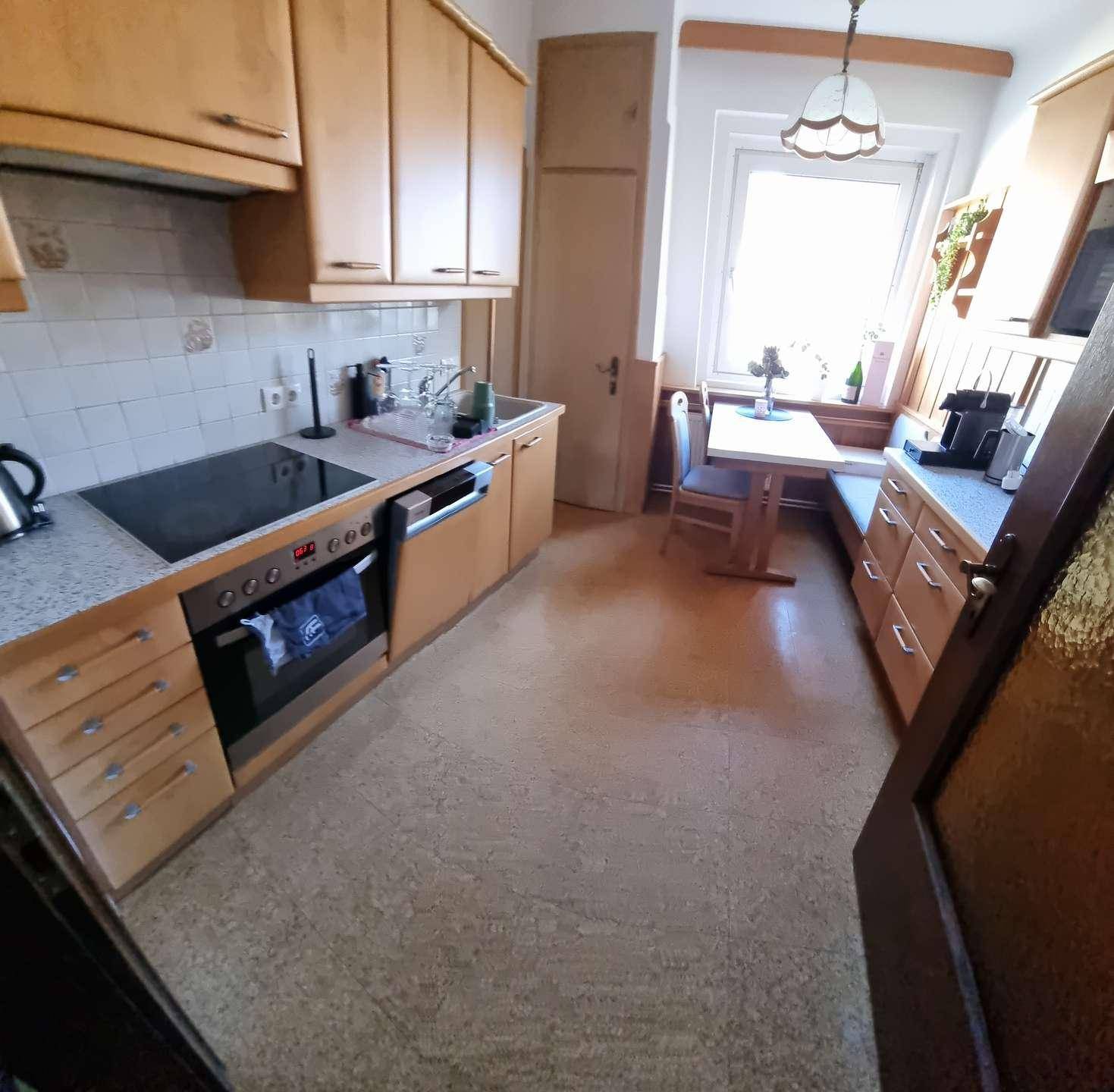 Gemütliche Küche mit Holzschränken, integrierten Geräten und einem kleinen Essbereich am Fenster.