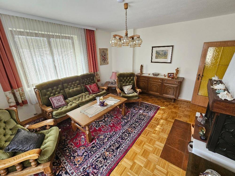 Geräumiges Wohnzimmer mit Kamin, Parkettboden und Blick auf den Garten.