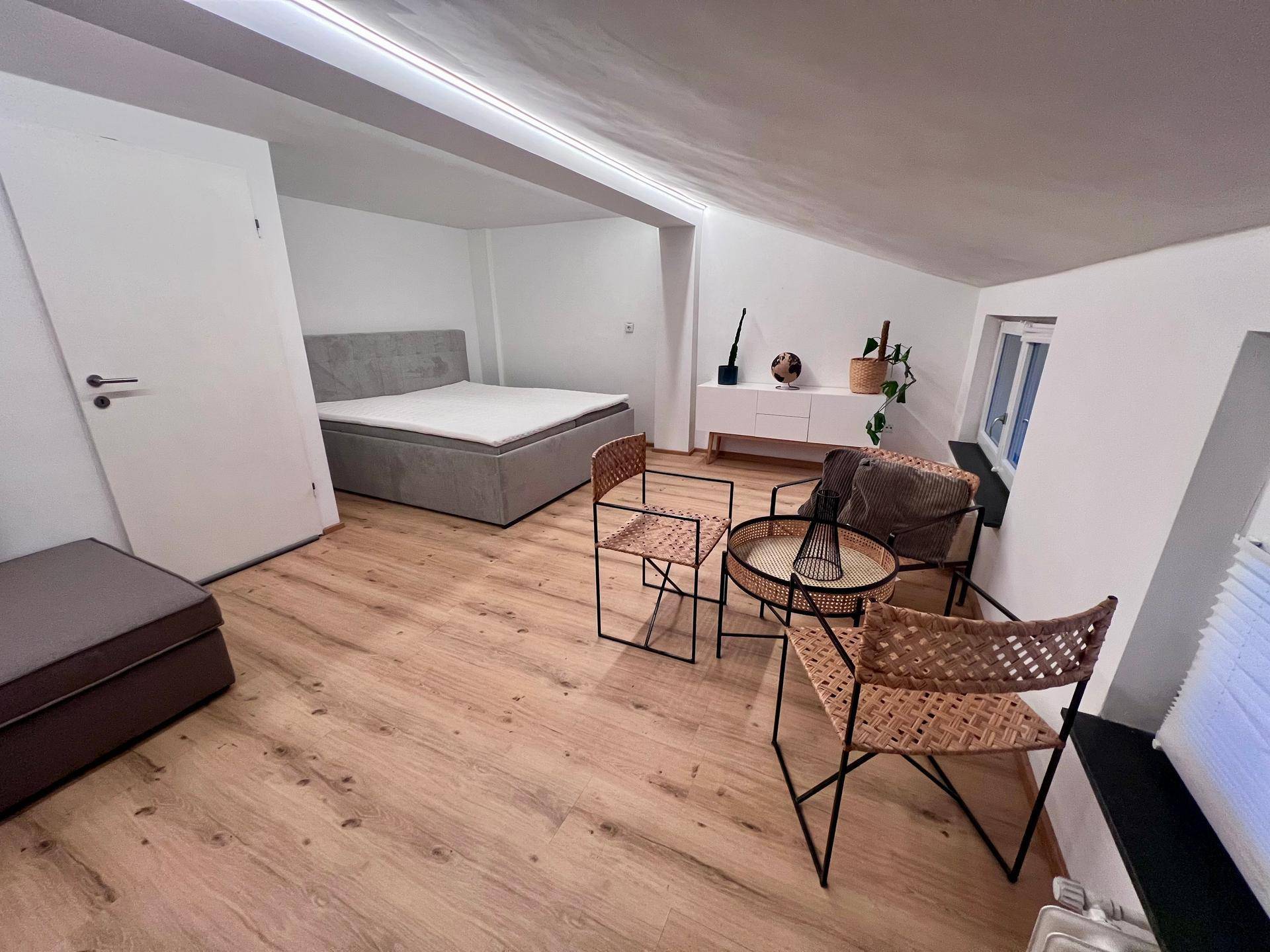 Gemütliches Schlafzimmer im Dachgeschoss mit Doppelbett, Sitzgelegenheiten und Holzboden.