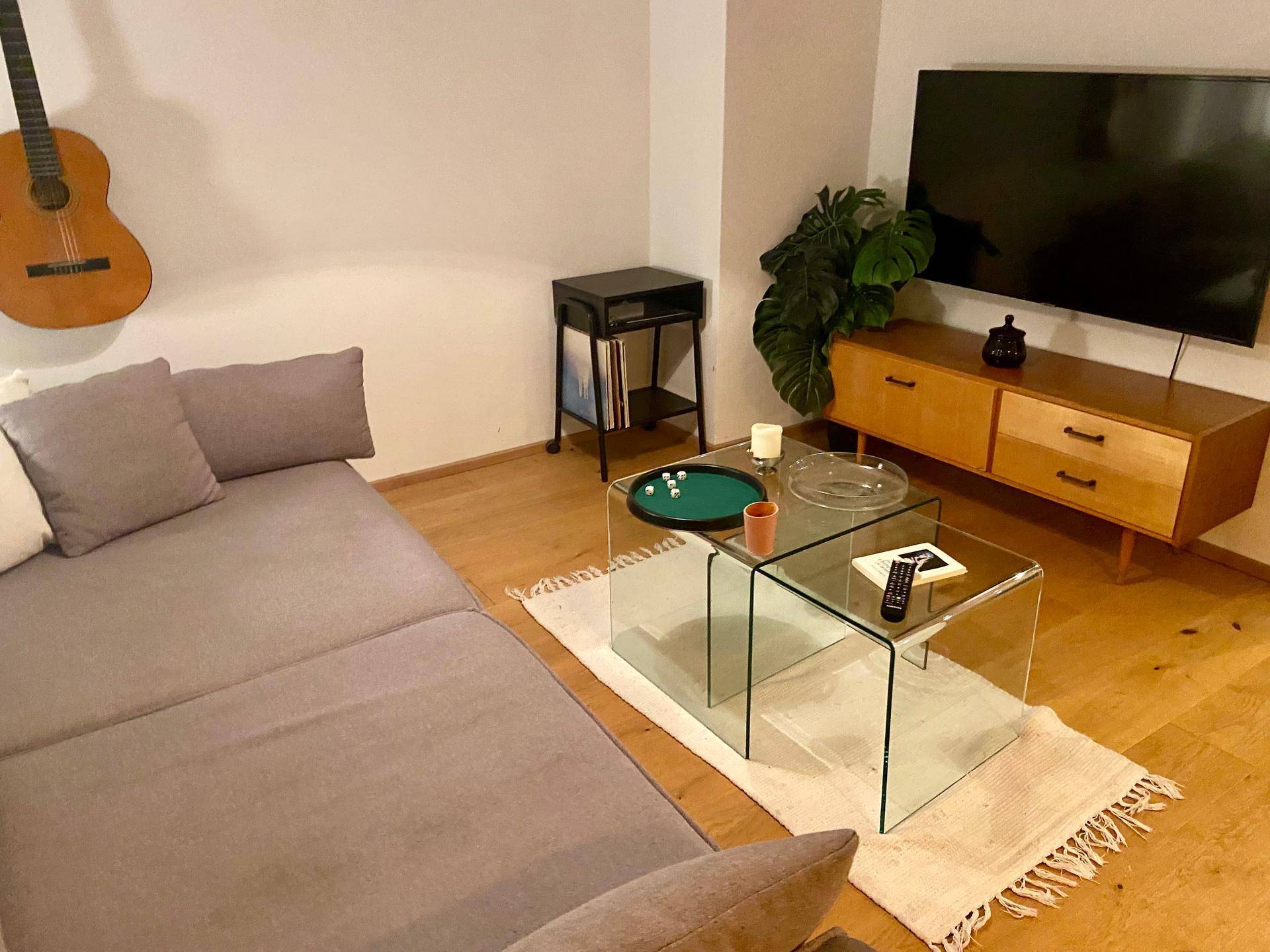 Detailansicht des Wohnbereichs mit bequemer Couch und modernen Glastischen auf einem Teppich.