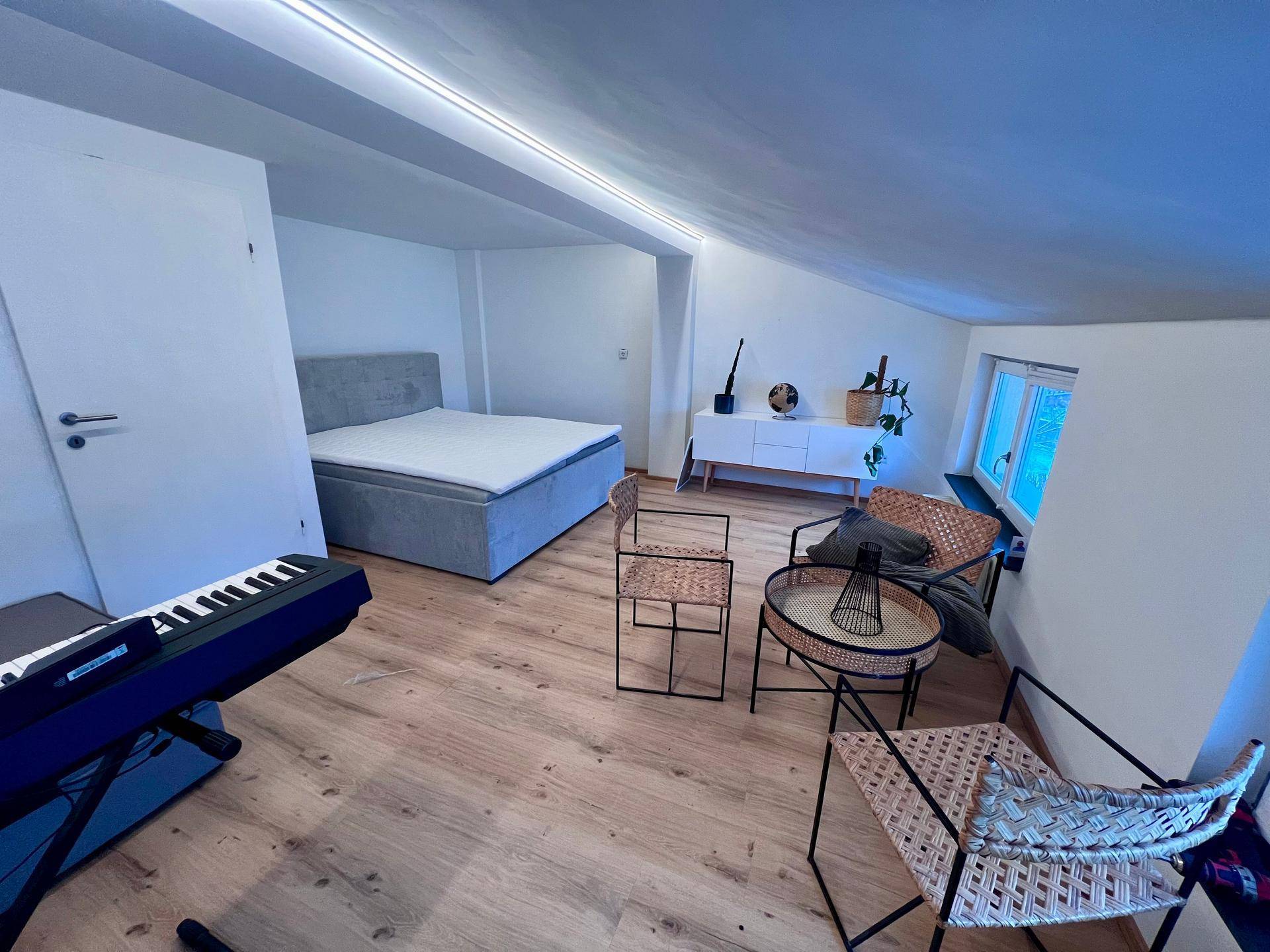 Geräumiges Schlafzimmer im Dachgeschoss mit Holzboden und schräger Decke.