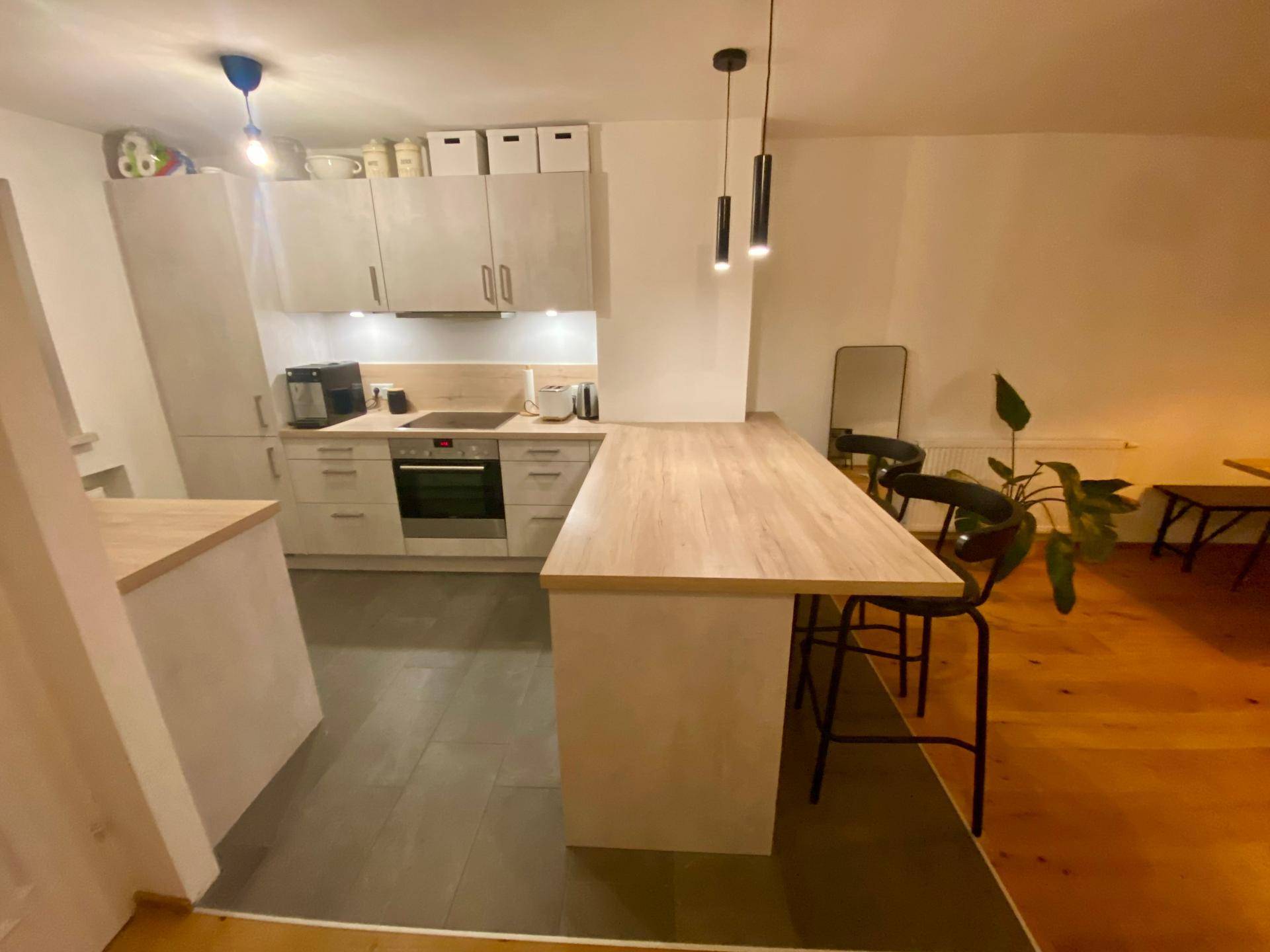 Moderne Küche mit hellen Schränken, integrierten Geräten und einer praktischen Frühstücksbar.