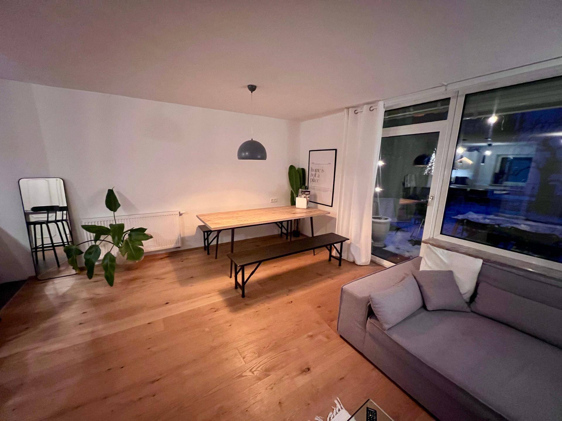 Heller Essbereich mit Holztisch und Zugang zu einem Außenbereich durch große Fenster.