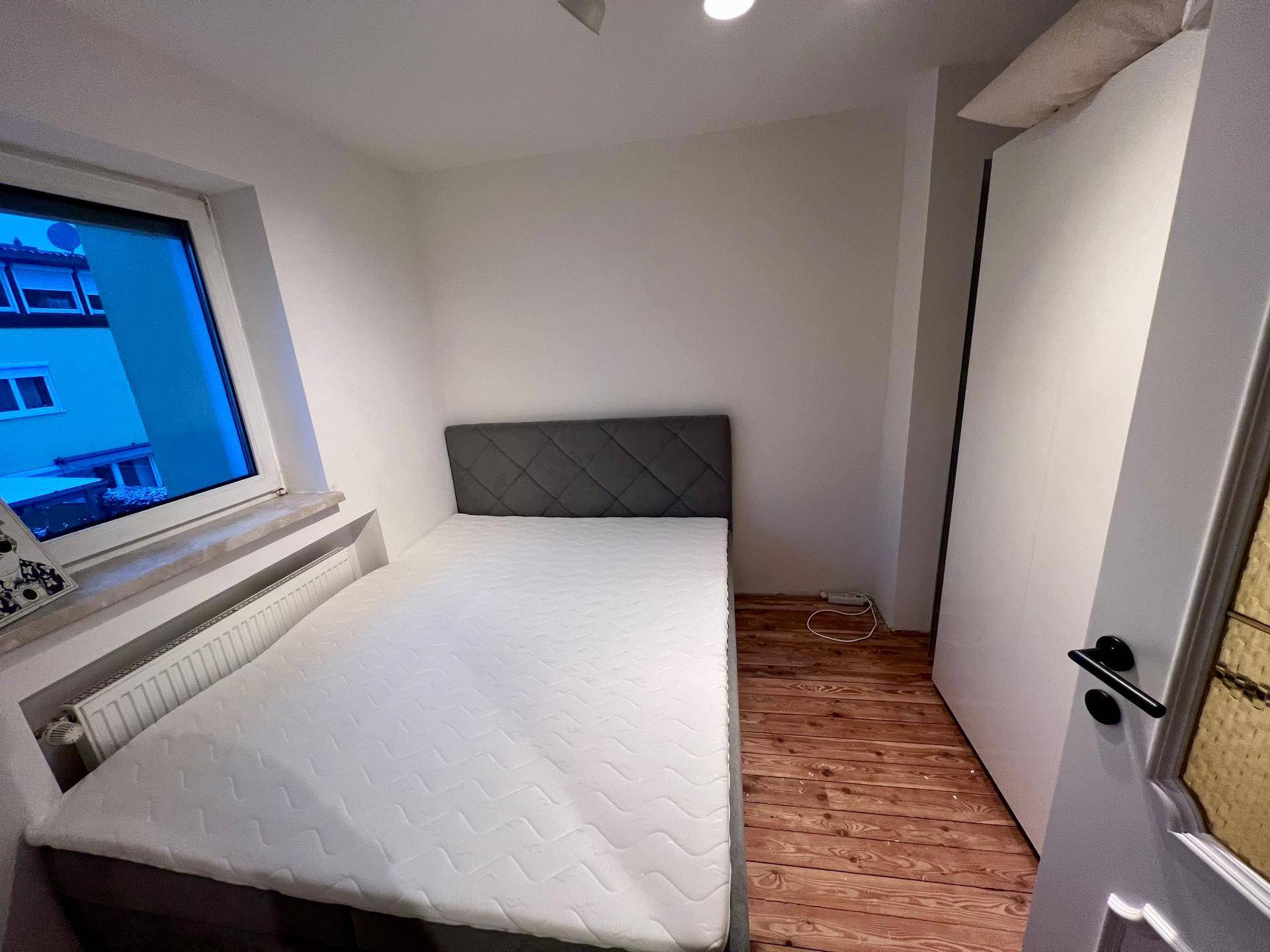 Gemütliches Schlafzimmer mit Doppelbett, Holzboden und weiß gestrichenen Wänden.