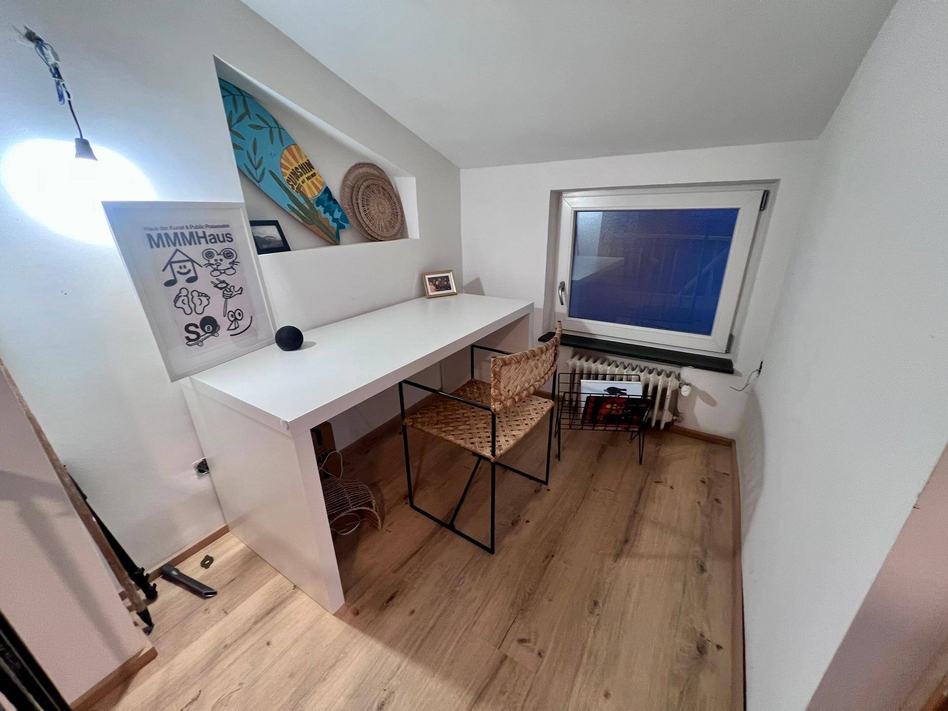 Helles Arbeitszimmer im Dachgeschoss mit Schreibtisch, Holzboden und Fenster.