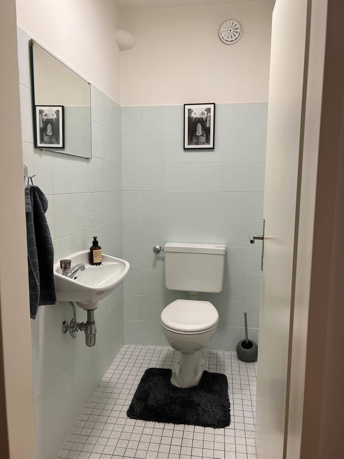 Kleines Gäste-WC mit Toilette, Waschbecken und hellblauen Wandfliesen.