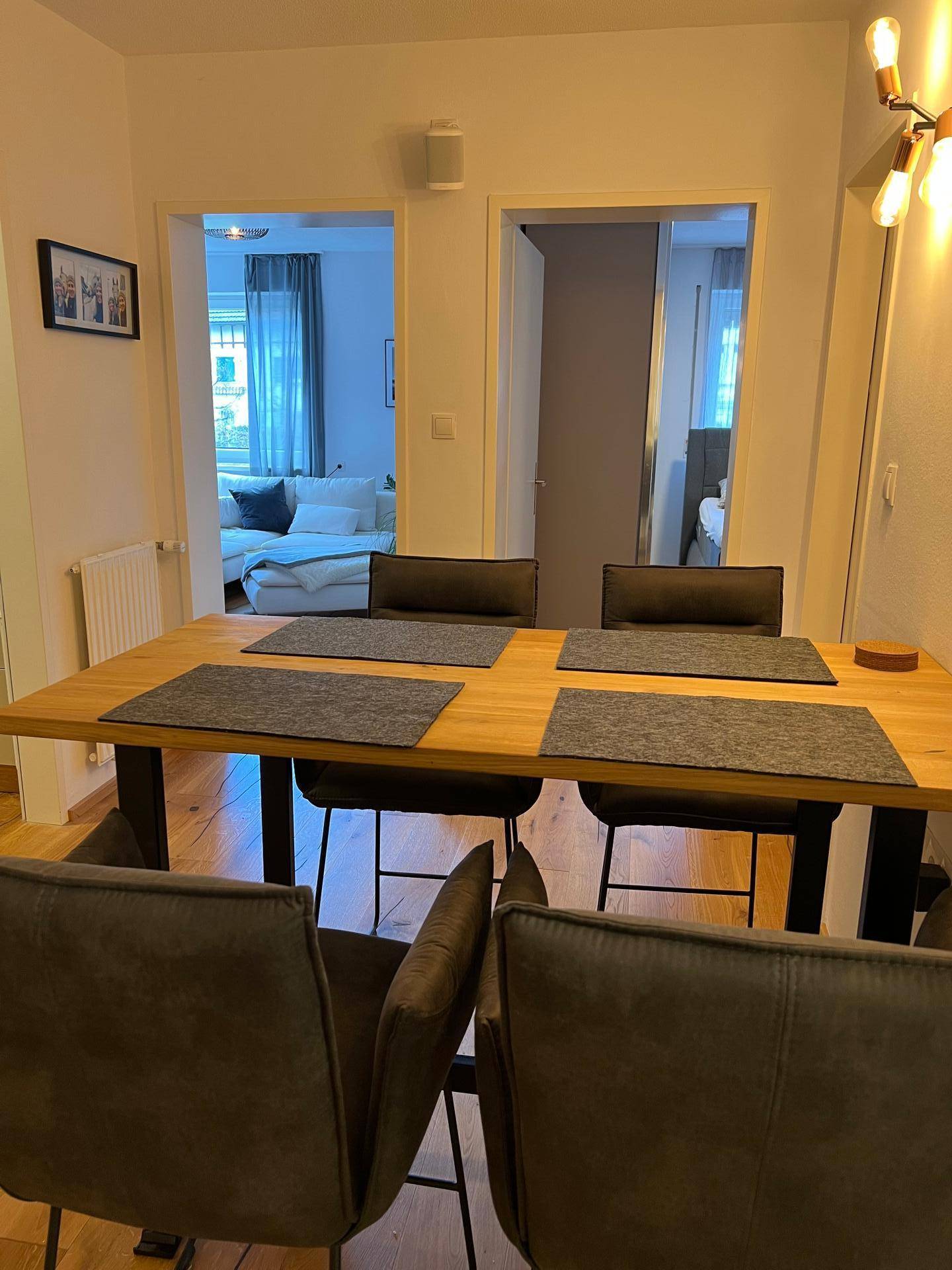 Essbereich mit Holztisch und Stühlen, der den Blick in angrenzende Wohnräume freigibt.