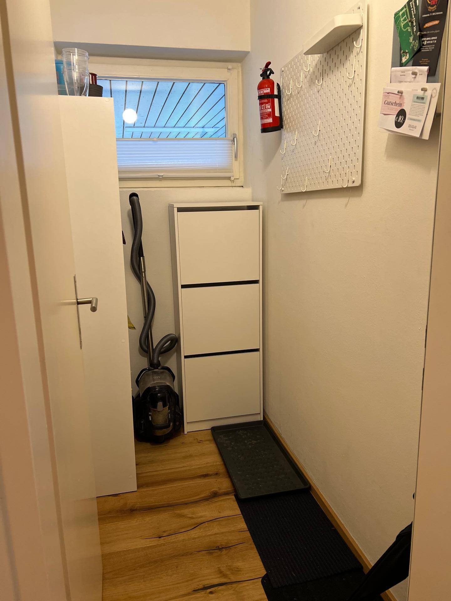 Heller Flur oder Abstellraum mit Fenster, Schuhschrank und Holzboden.