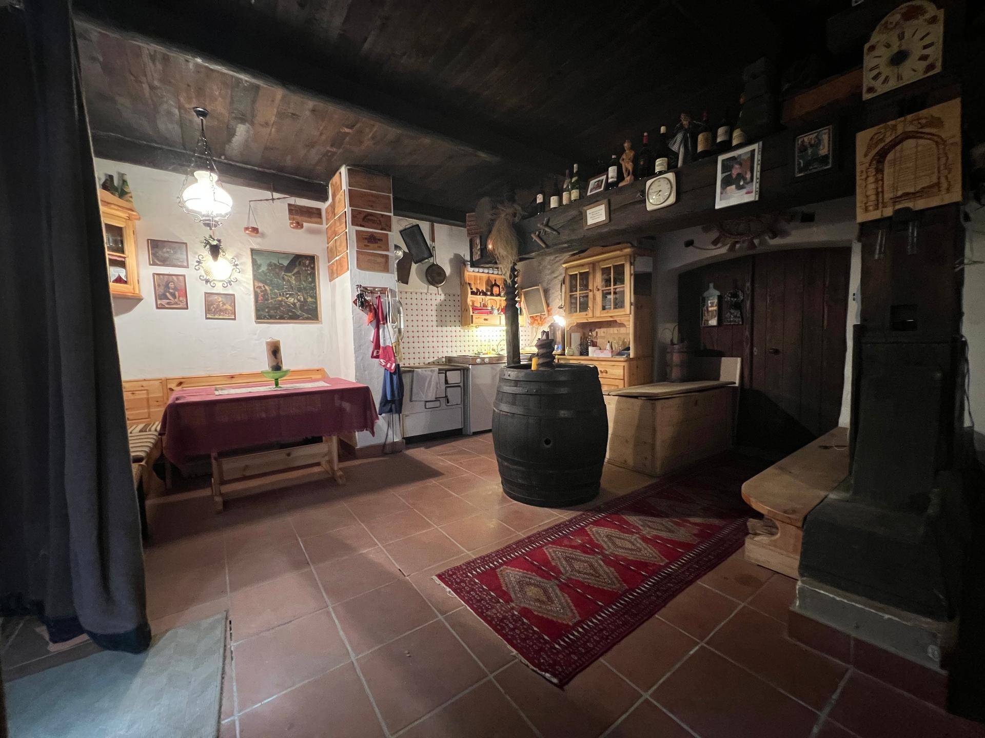 Rustikaler Wohn- und Essbereich mit Holzbalkendecke, Fliesenboden und traditioneller Einrichtung.