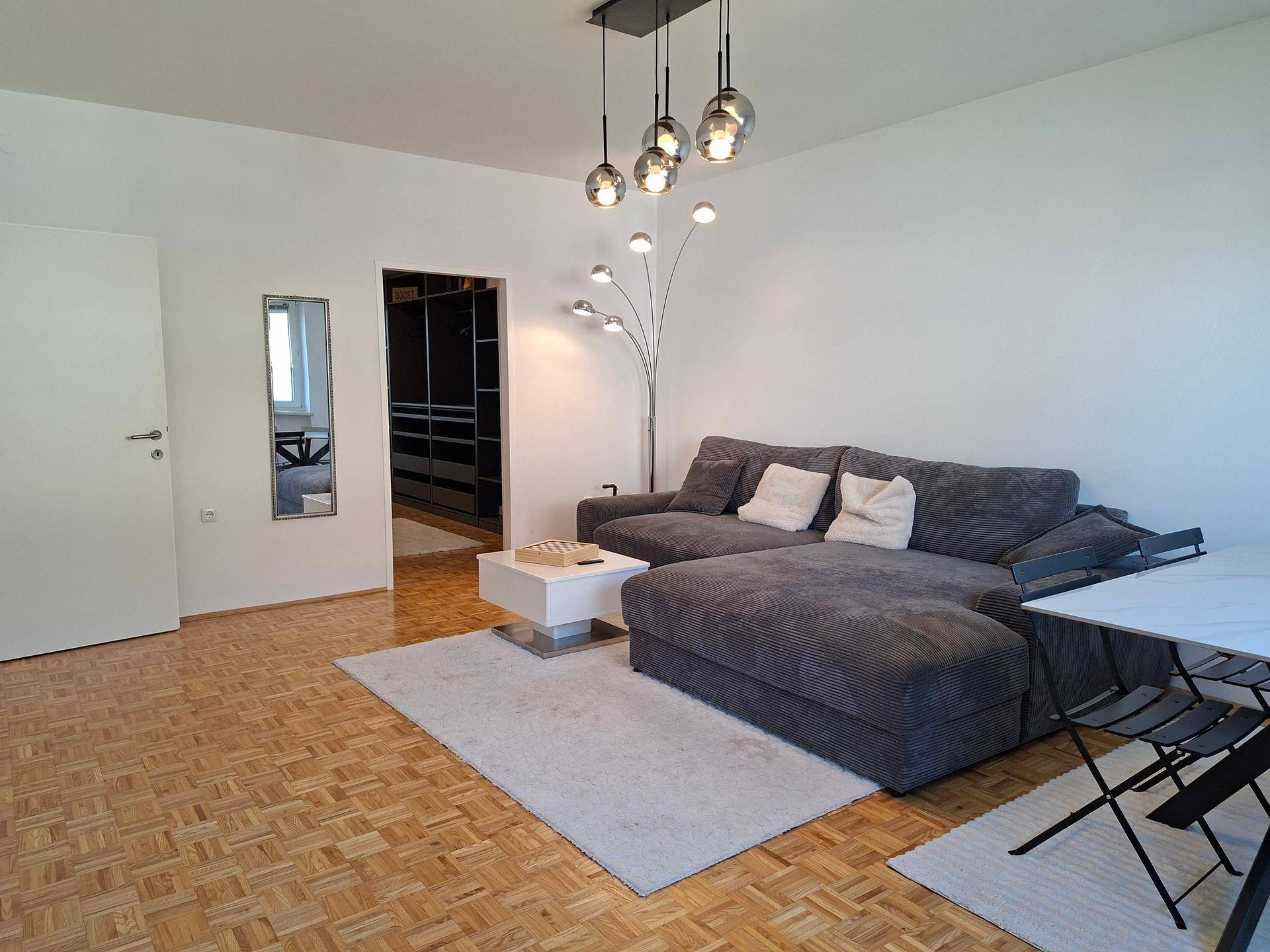 Gemütliches Wohnzimmer mit großem Ecksofa, Parkettboden und moderner Beleuchtung.