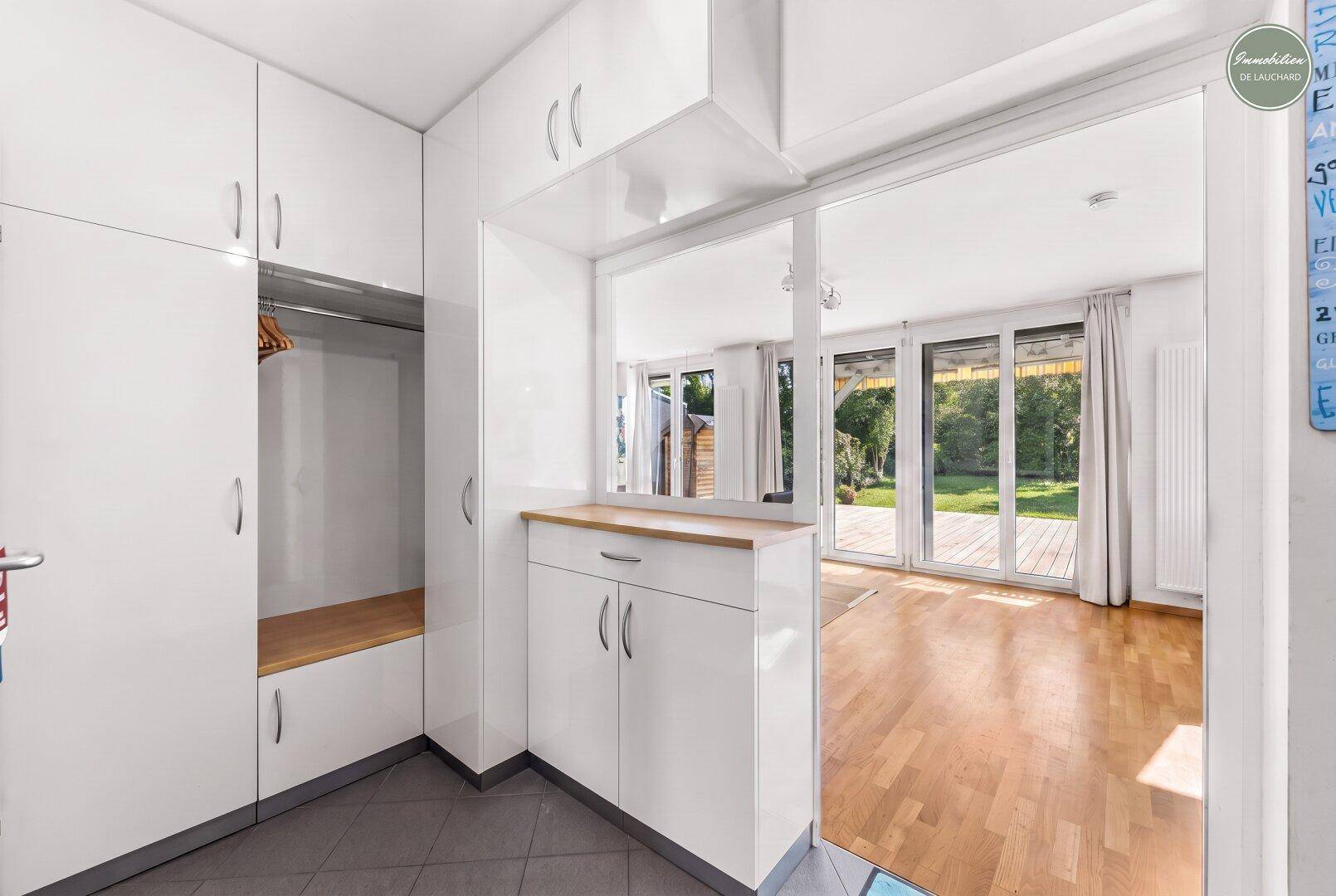 Heller Eingangsbereich mit Einbauschränken, Garderobe und Blick in den Wohnbereich.