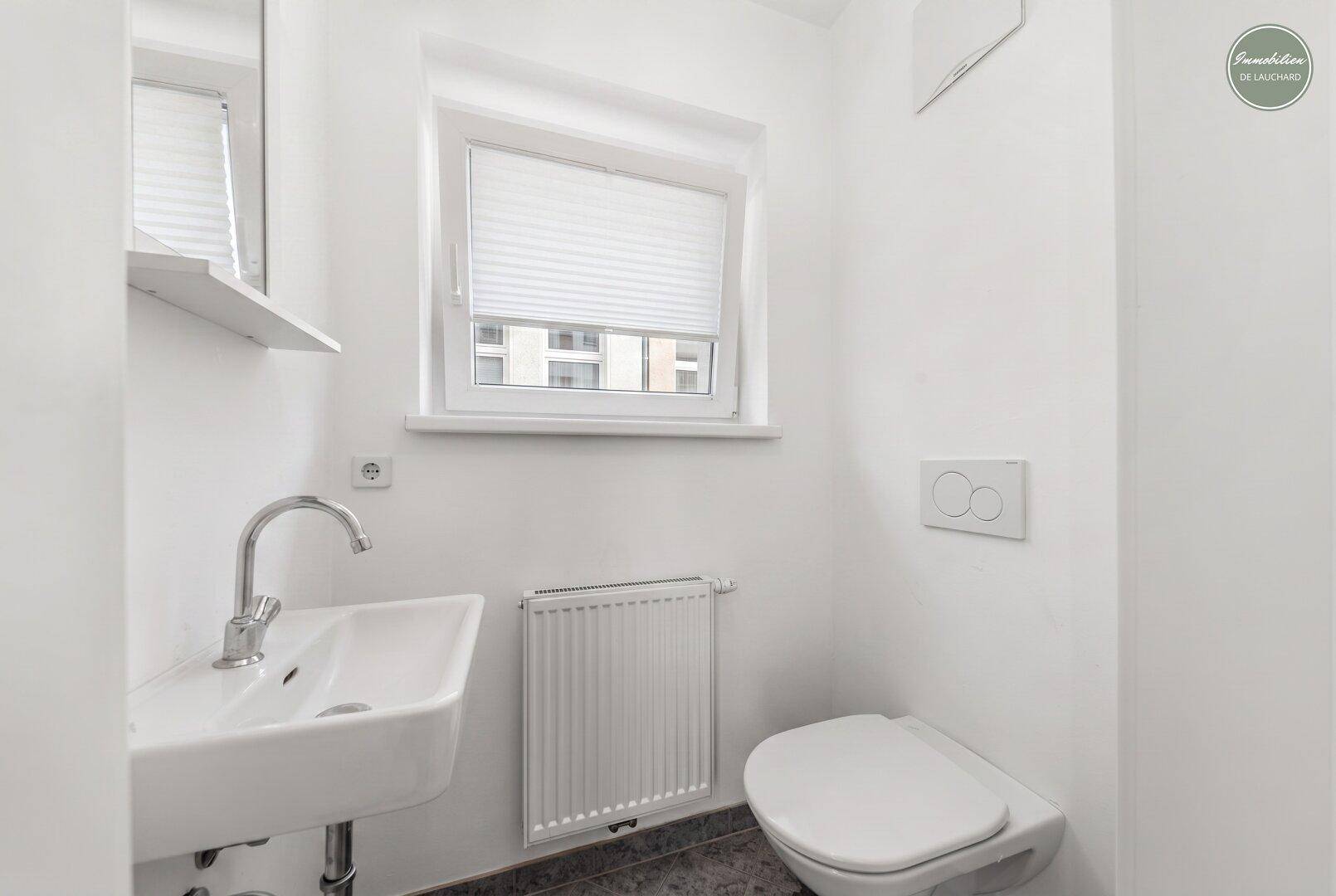 Modernes Gäste-WC mit Fenster, wandhängendem WC und kleinem Waschbecken.