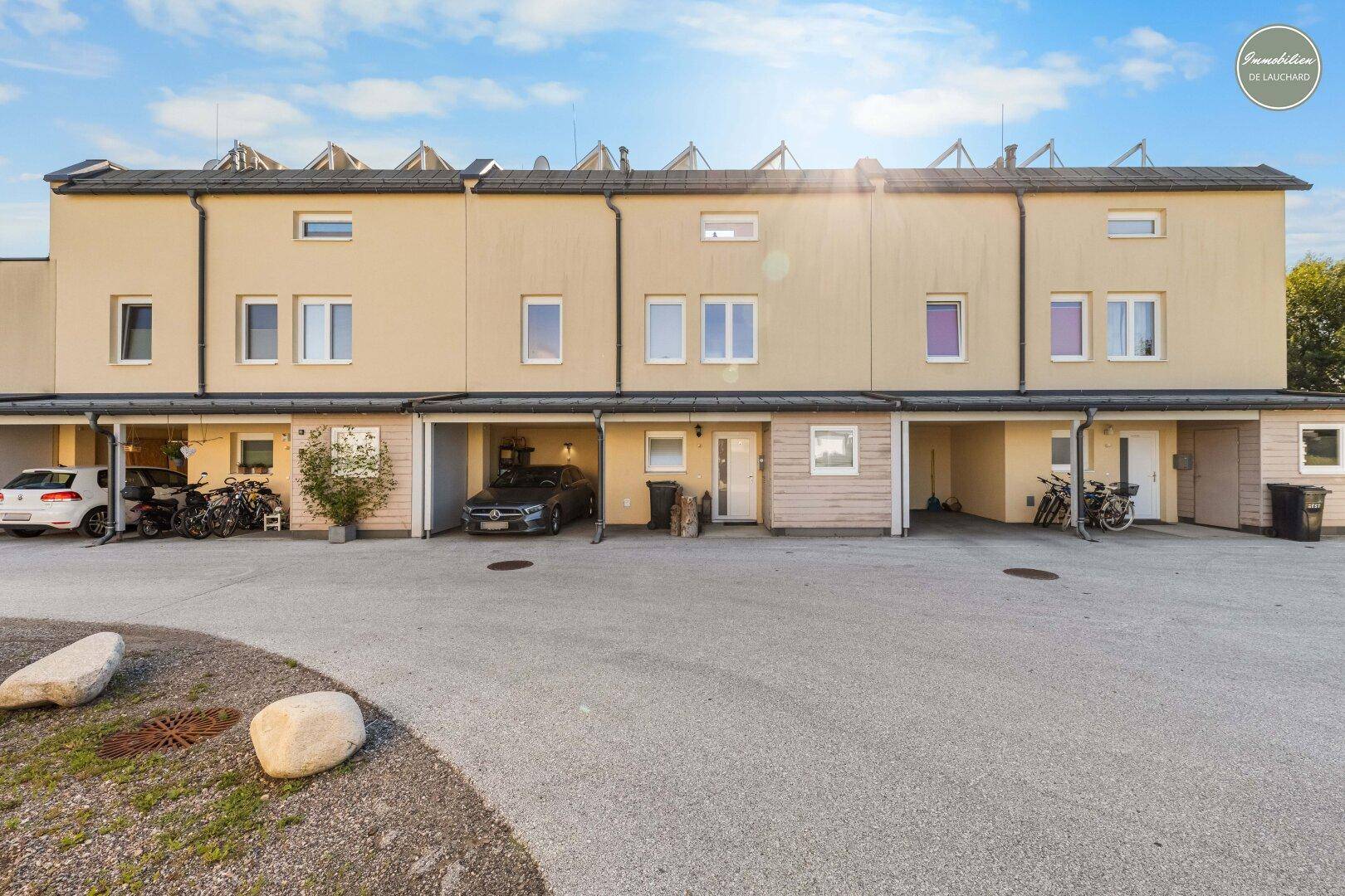 Reihenhäuser mit Carports und Parkplätzen vor der modernen Fassade.