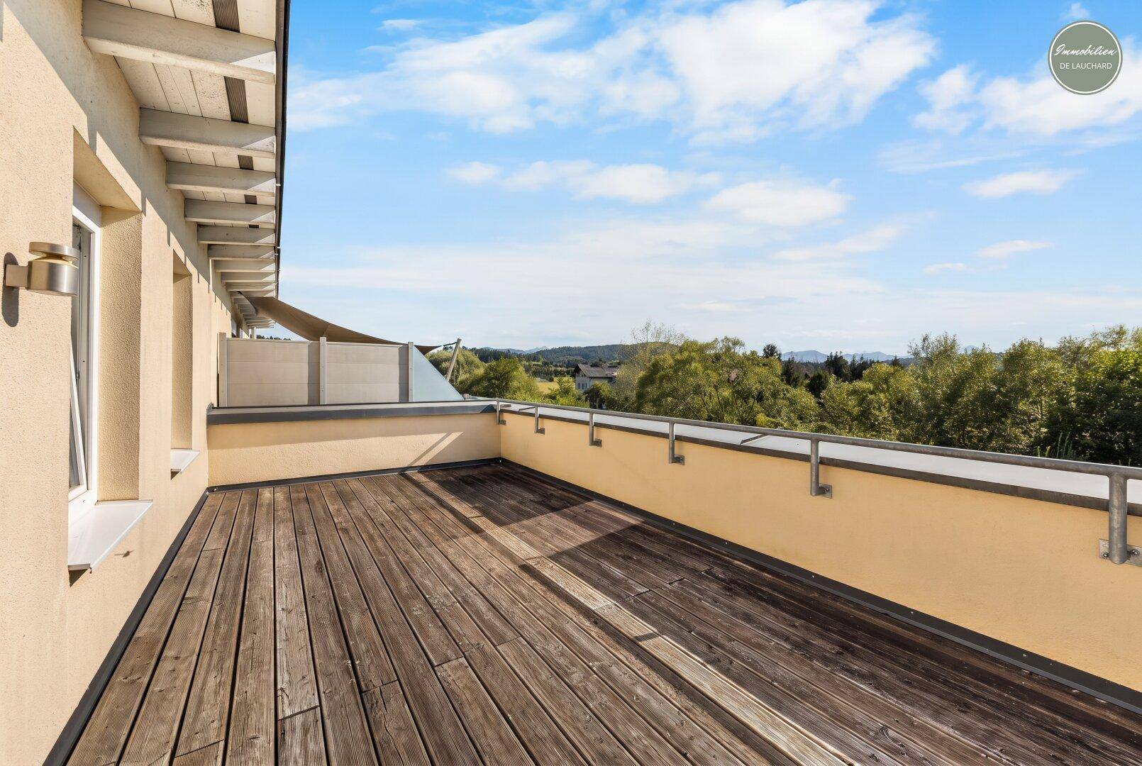 Geräumige Holzterrasse mit Panoramablick über die Landschaft und viel Sonnenlicht.