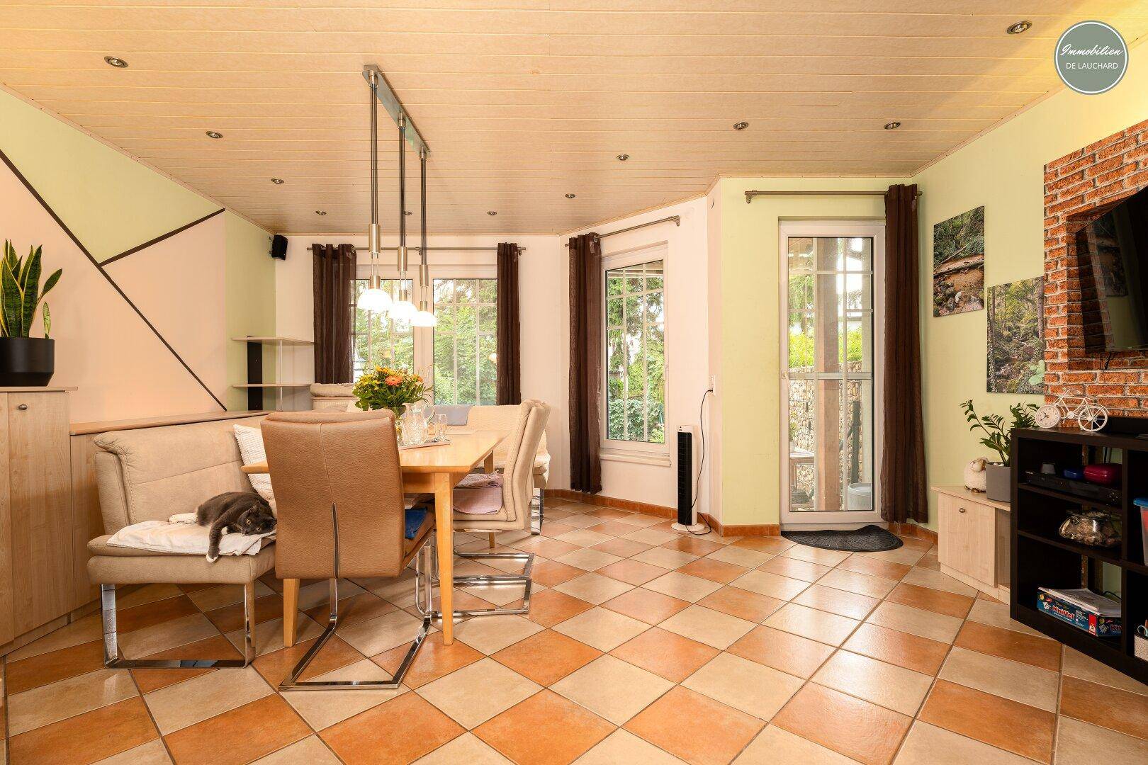 Heller Essbereich mit großem Holztisch, Fliesenboden und Holzdeckenverkleidung.