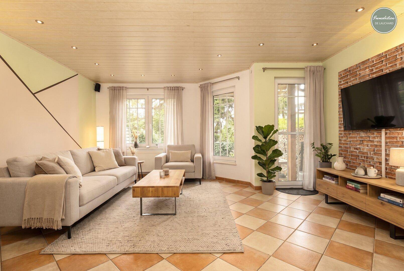 Gemütliches Wohnzimmer mit hellem Sofa, Couchtisch und Fliesenboden.