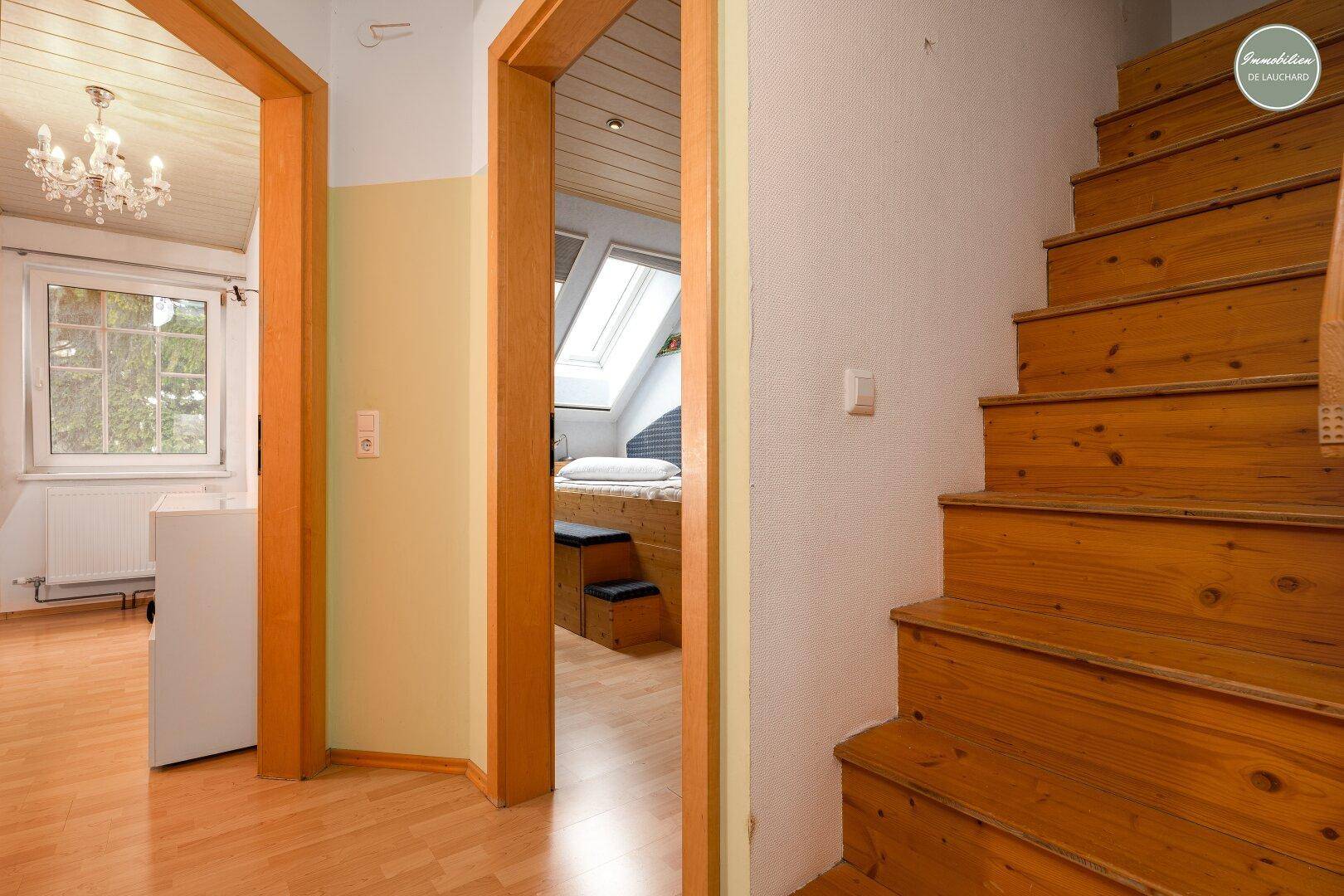 Heller Flur mit Zugang zu verschiedenen Zimmern und Holztreppe.