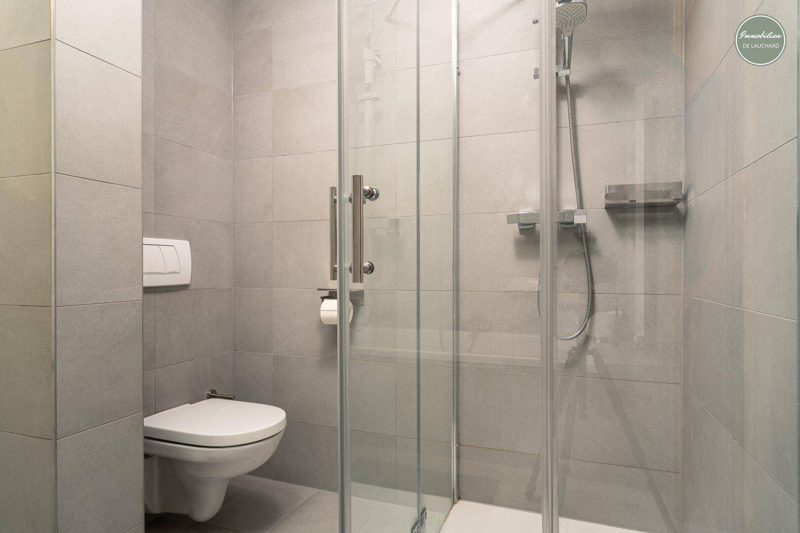Duschbereich mit Glasabtrennung und wandhängendem WC in modernem Badezimmer.