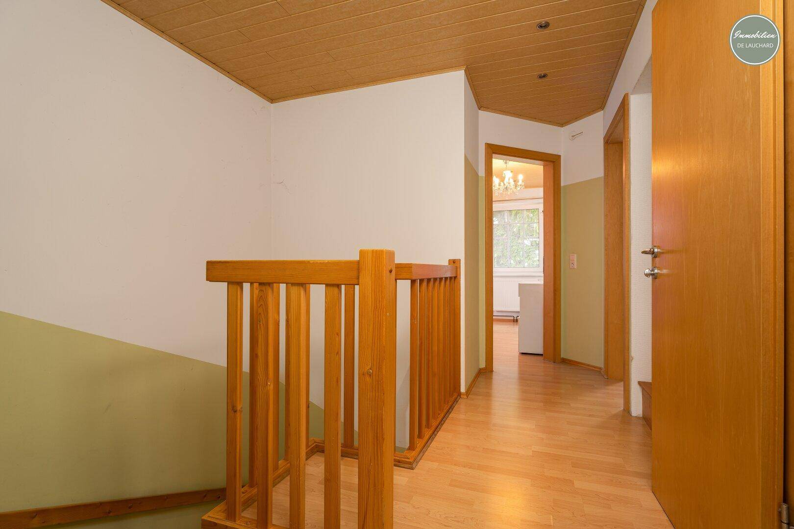 Flur mit Holztreppe und Laminatboden, der zu den oberen Etagen führt.