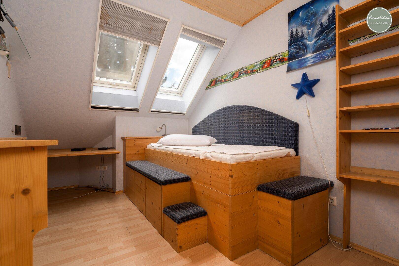 Kinderzimmer mit eingebautem Holzbett, Regalen und Dachfenstern für viel Licht.