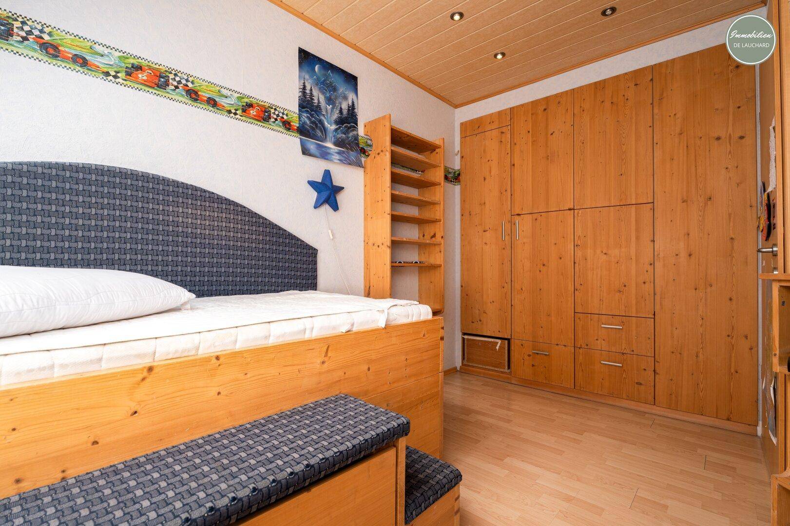 Schlafzimmer mit maßgefertigten Holzschränken, Holzbett und Laminatboden.