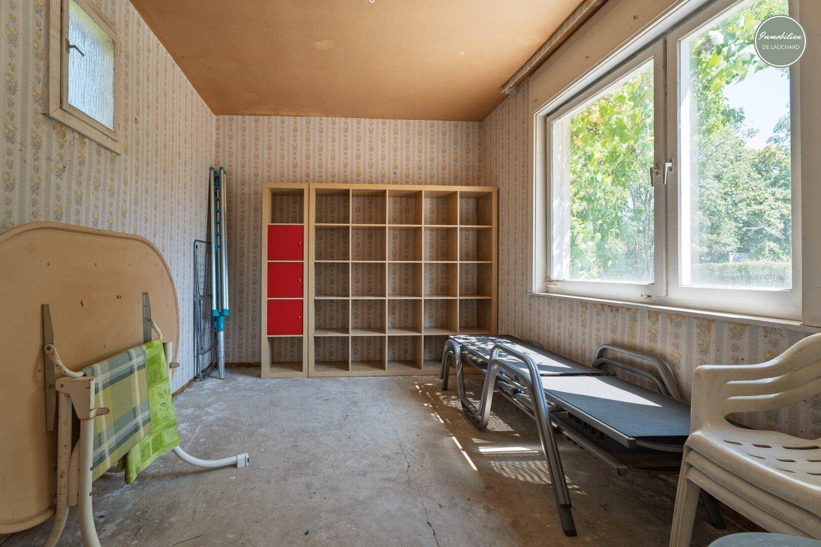 Geräumiger Abstellraum mit Regalen, Fenster und einfacher Ausstattung, ideal für Lagerung.