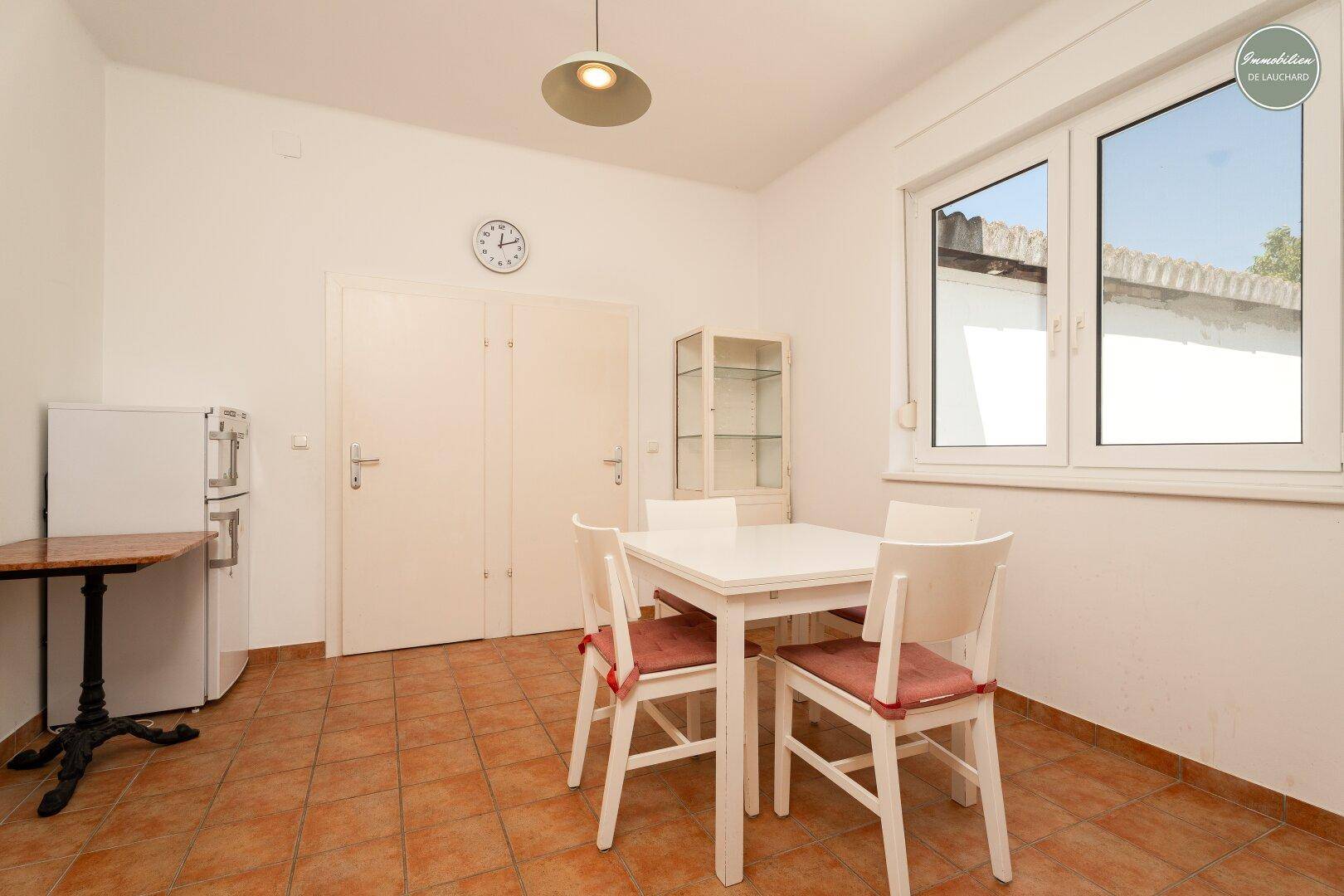 Essbereich mit weißem Tisch, Stühlen und einem Kühlschrank, ideal für Mahlzeiten.