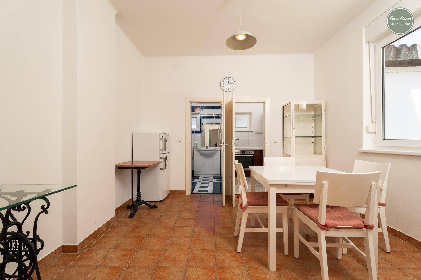 Essbereich mit Terrakottafliesen und offenem Zugang zur Küche und zum Badezimmer.
