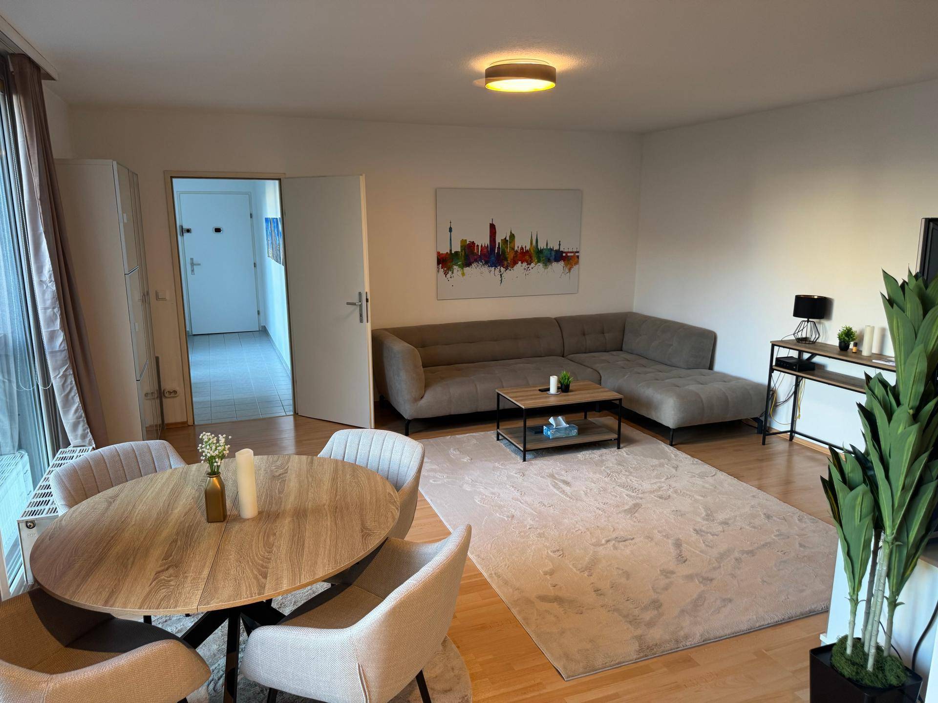 Gemütlicher Wohnbereich mit Ecksofa, Esstisch und Blick auf die Stadt.