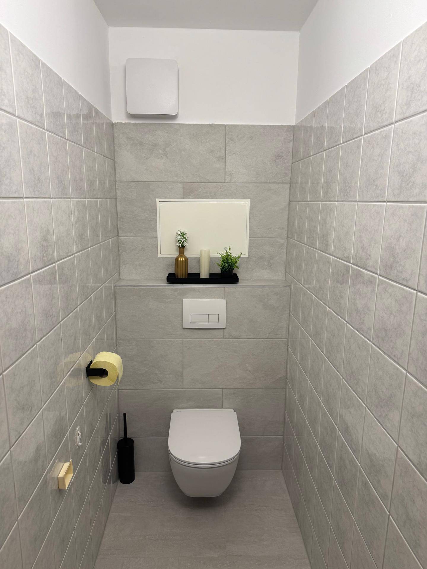 Modernes Gäste-WC mit grauen Fliesen und wandhängendem WC.