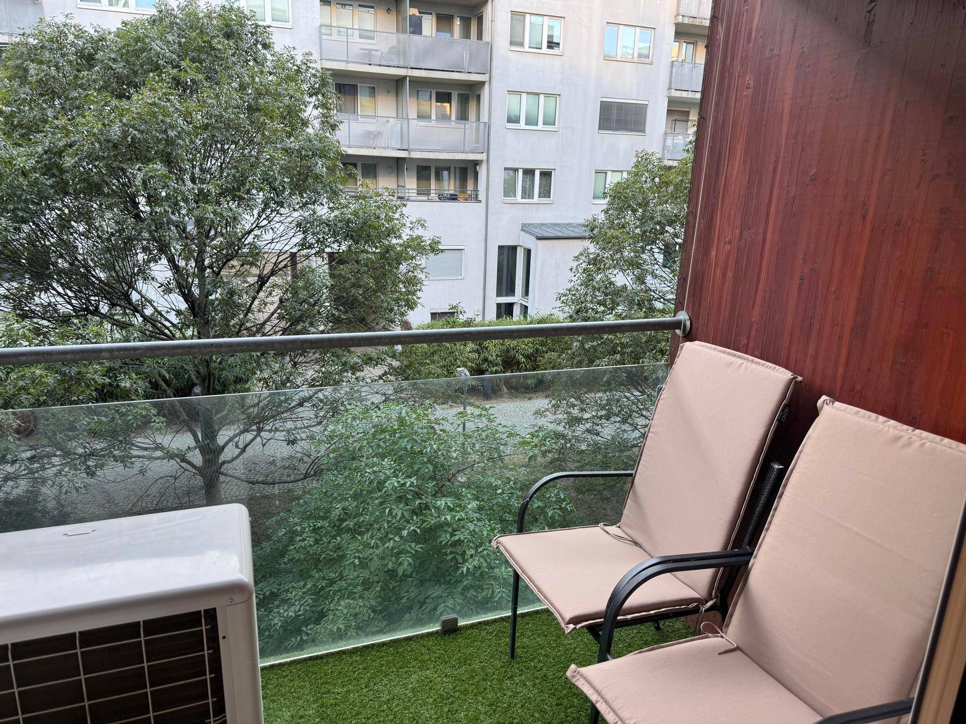 Balkon mit Sitzgelegenheiten und Blick auf die umliegenden Gebäude und Bäume.