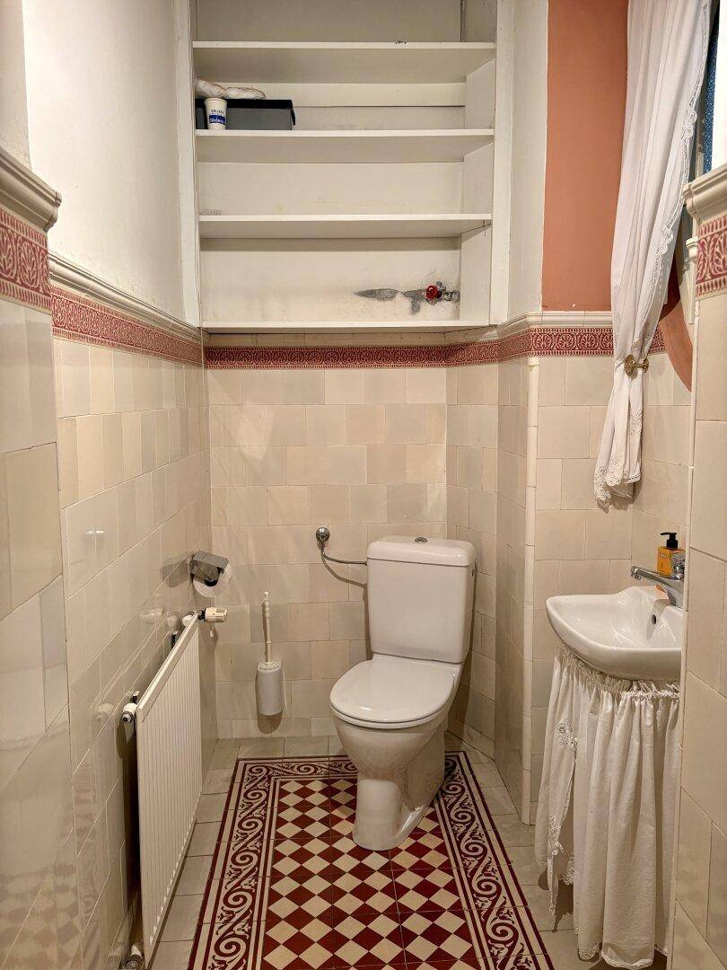 Kleines Gäste-WC mit traditionellen Fliesen, Toilette und Waschbecken, funktional und sauber.