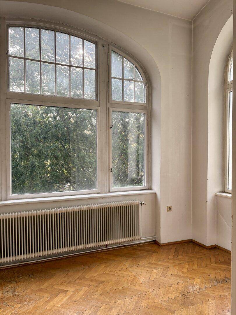 Große Rundbogenfenster mit Blick auf Bäume, die den Raum mit natürlichem Licht füllen.