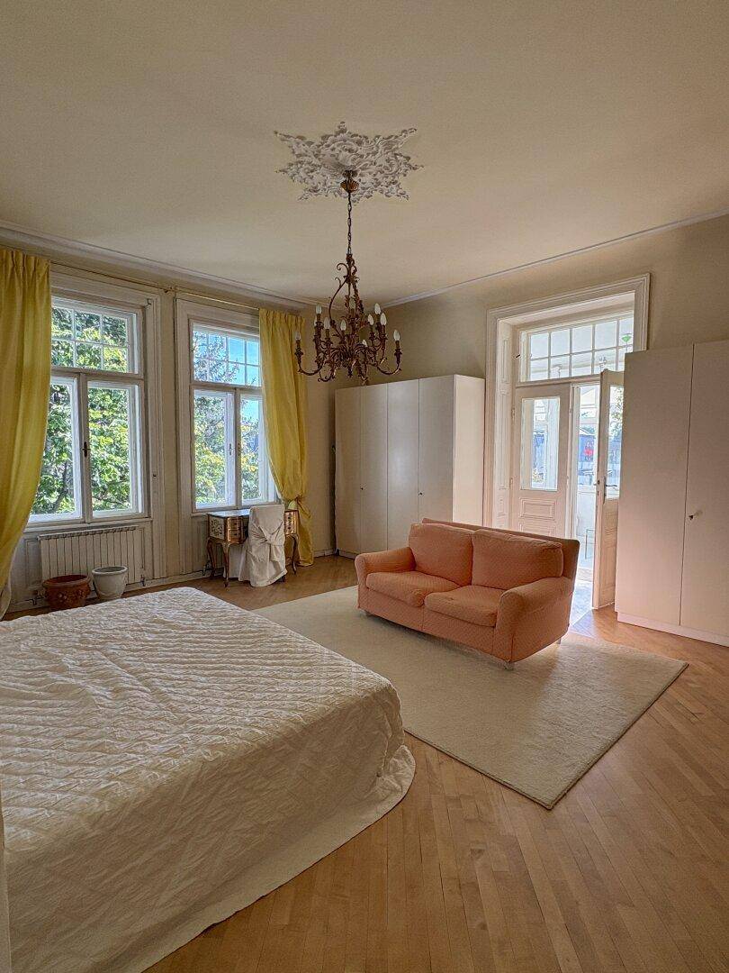 Geräumiges Schlafzimmer mit hohen Decken, Stuckverzierung und traditionellem Kronleuchter.