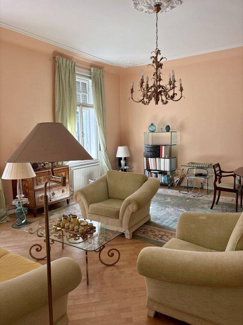 Gemütliches Wohnzimmer mit traditionellen Möbeln, Kronleuchter und Teppichboden.