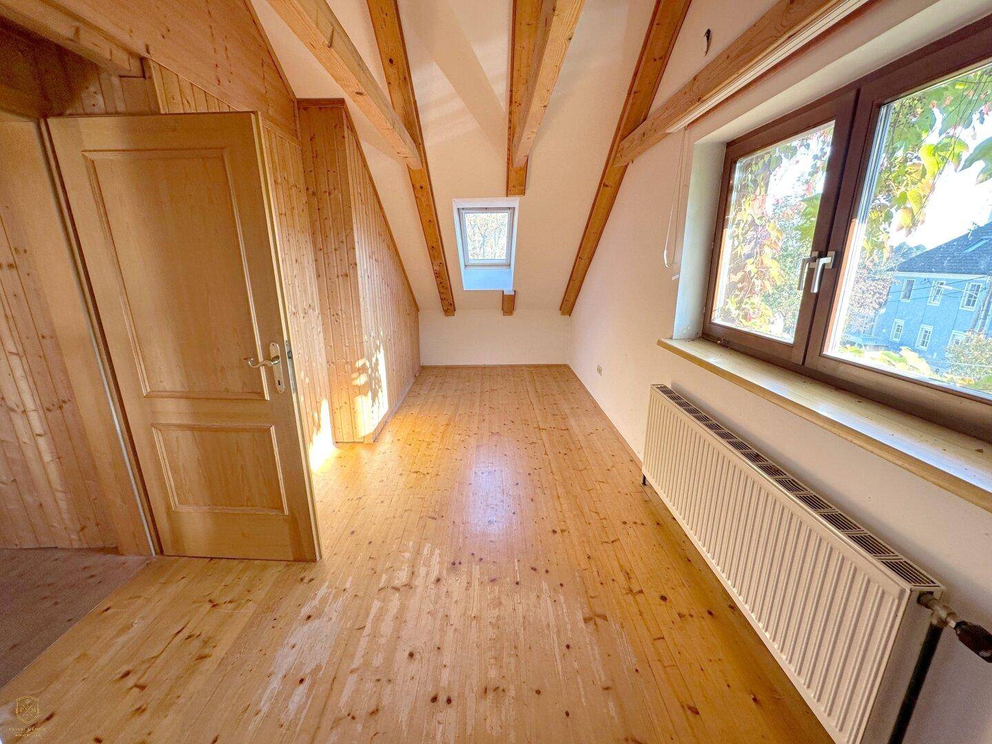Helles Schlafzimmer mit Holzdielenboden, Dachschräge und Holzvertäfelung.